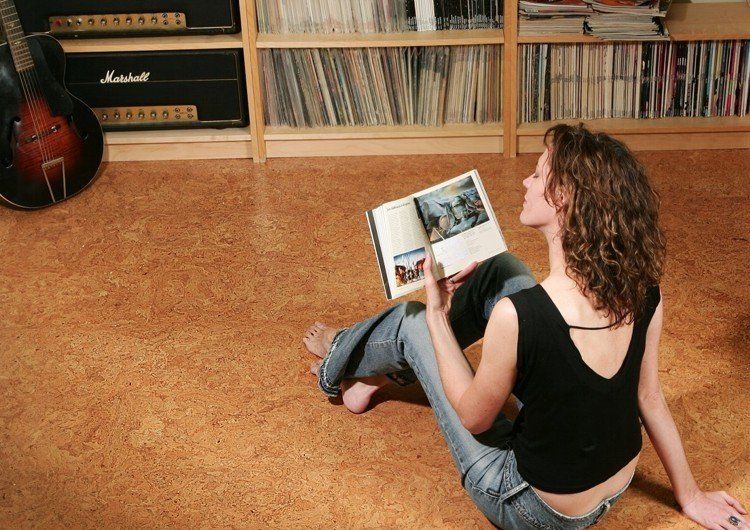 A woman is sitting on the floor reading a book