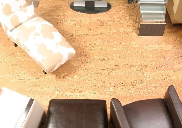 A living room with chairs and ottomans on a cork floor