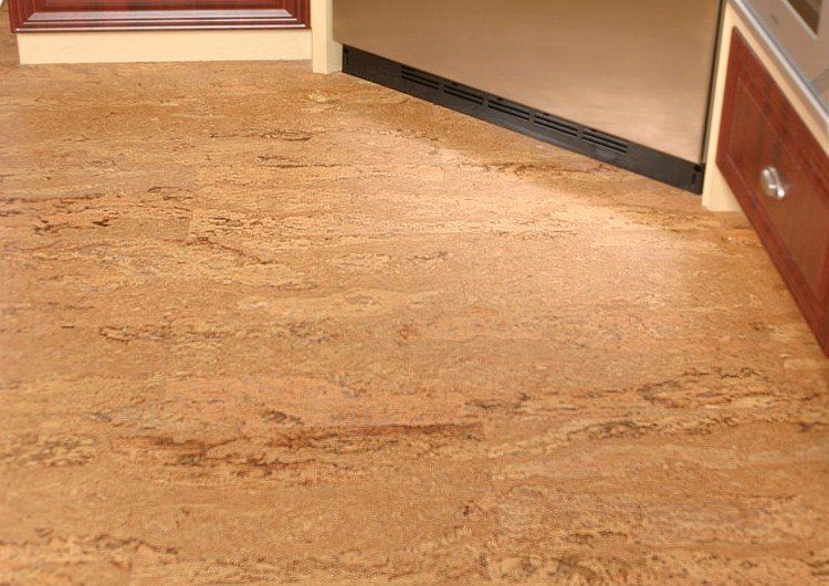 A kitchen with a cork floor and wooden cabinets.