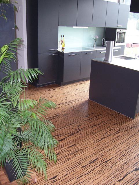 A kitchen with black cabinets and a wooden floor