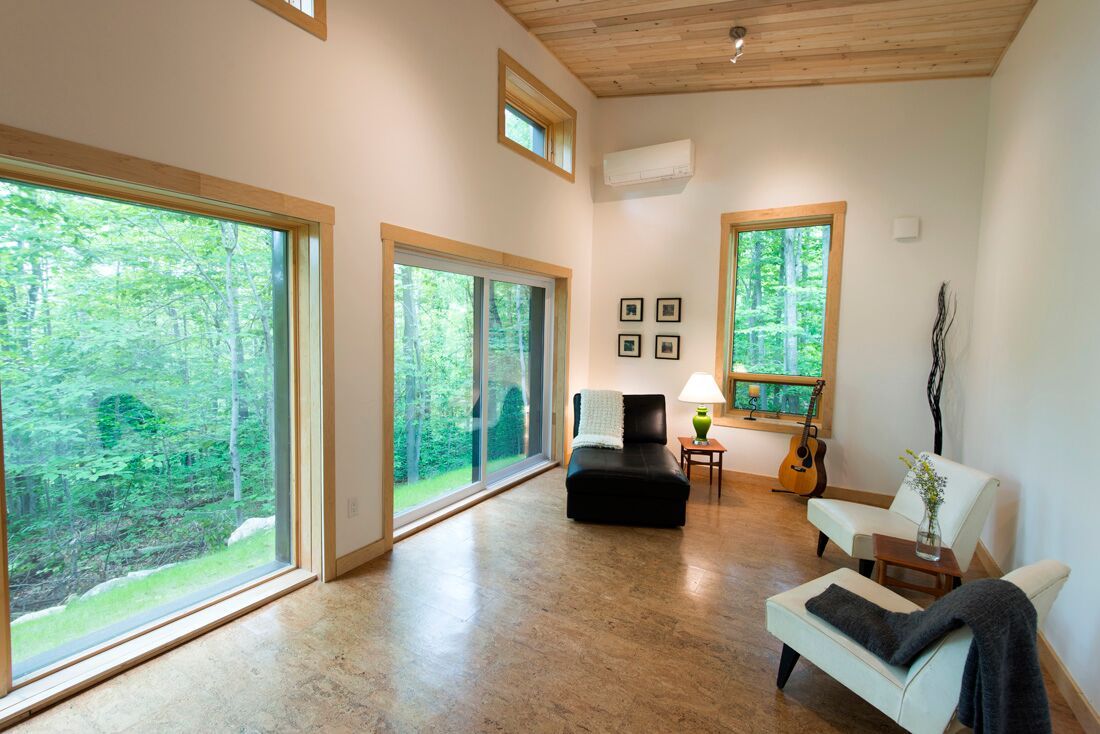 A living room with a lot of windows and a guitar.