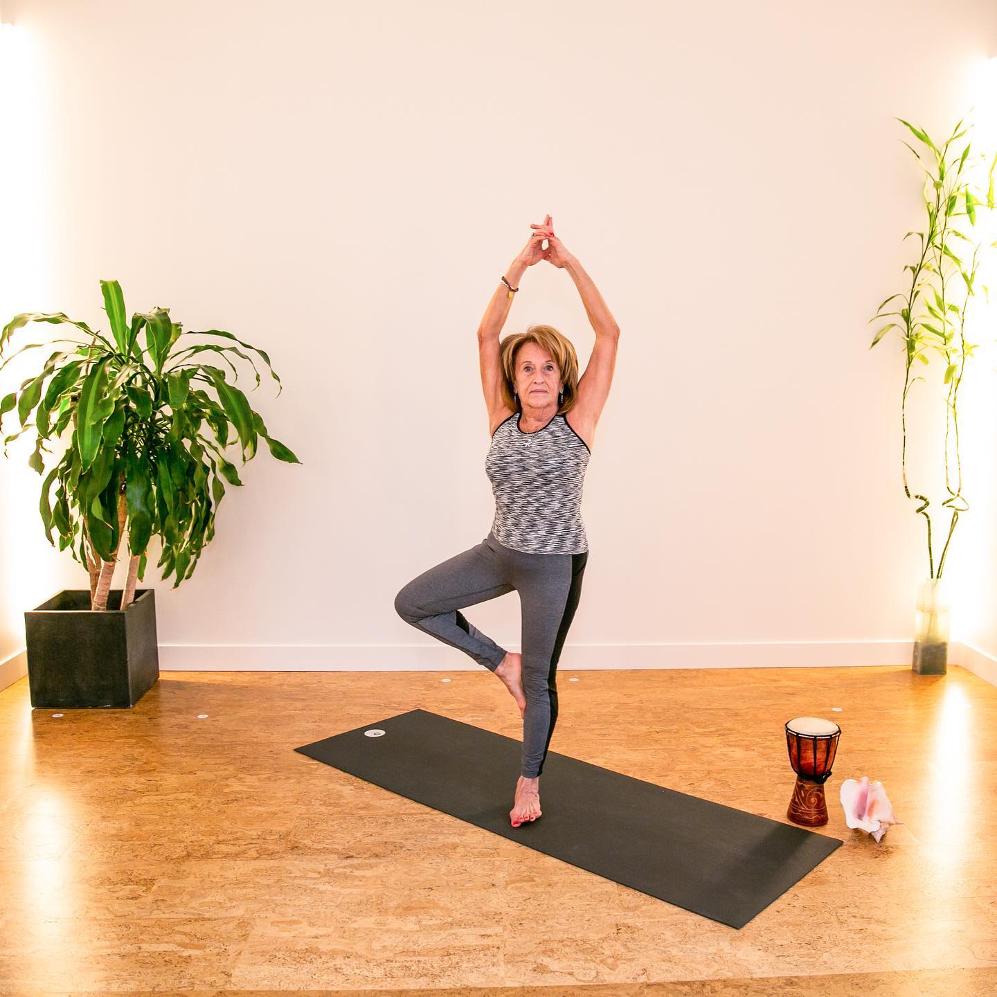 A woman is standing on one leg on a yoga mat
