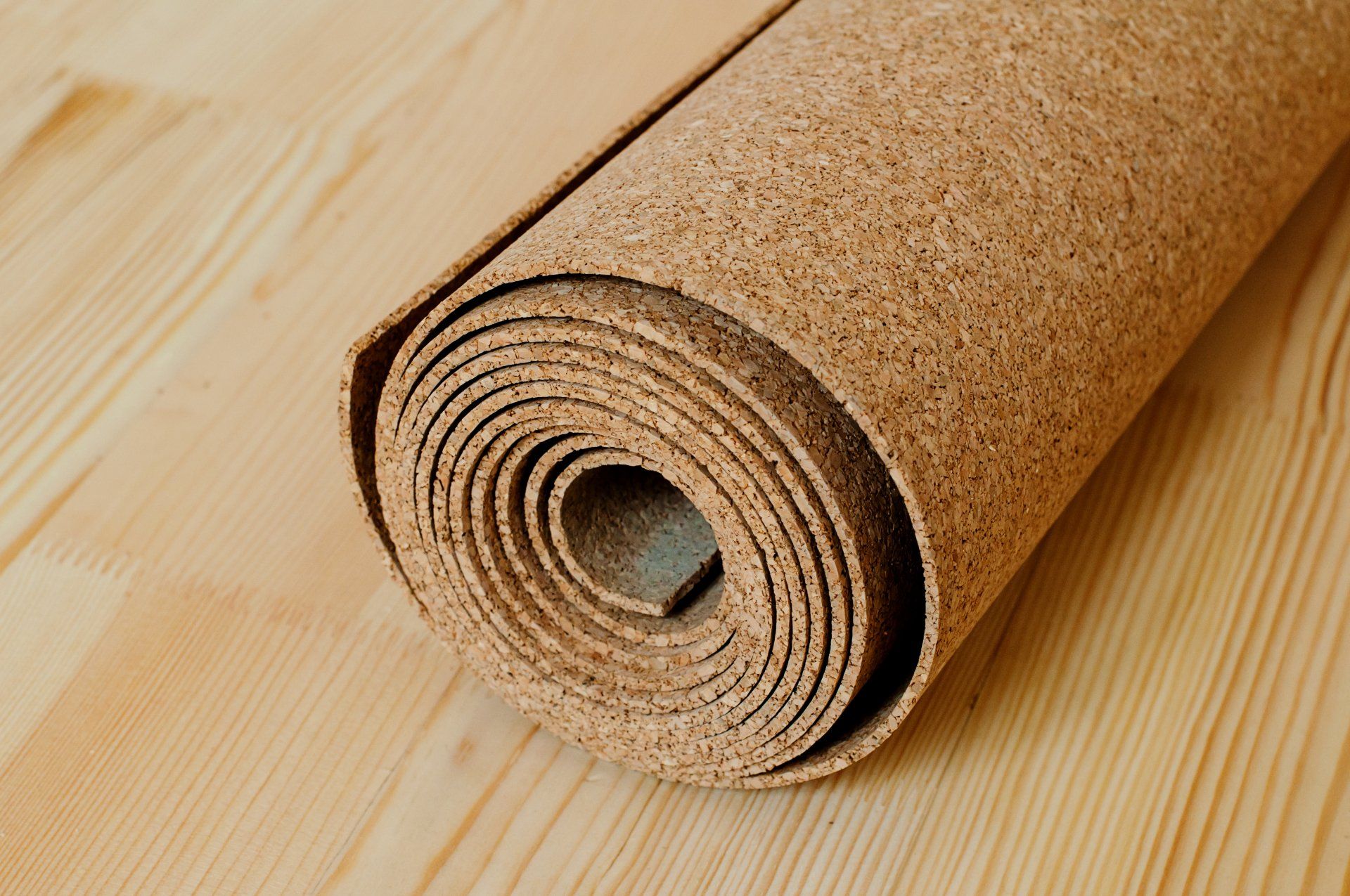 Tapis en liège roulé sur parquet en bois clair.