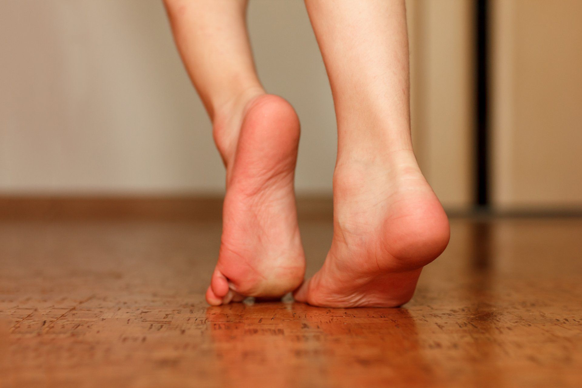 A woman 's bare feet are walking on a wooden floor.