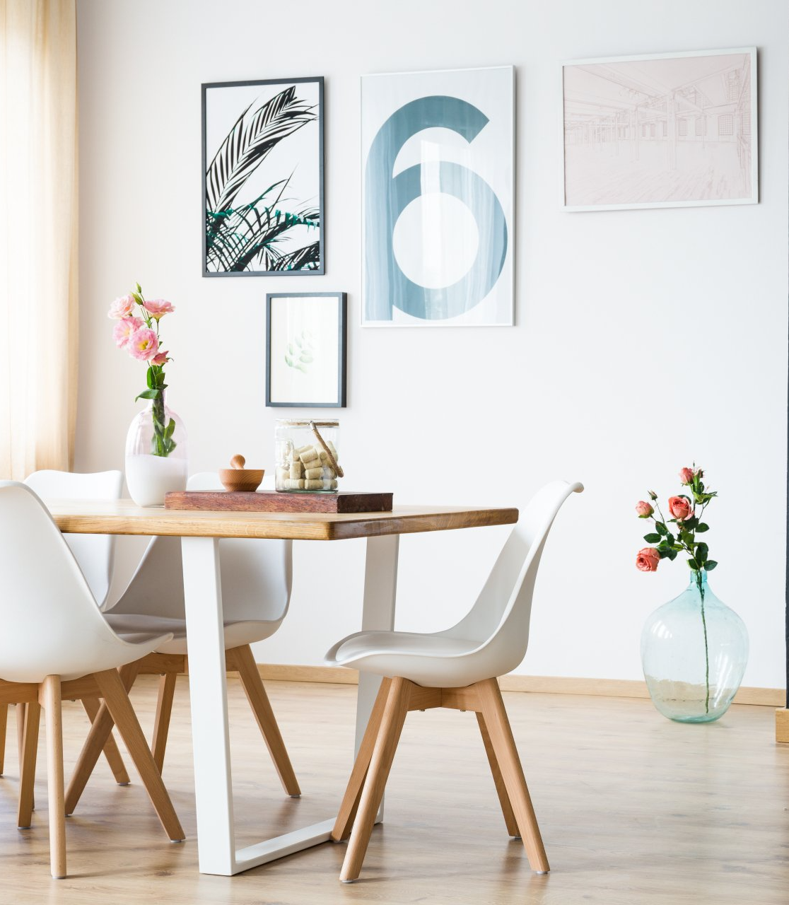 A dining room with a table and chairs and a vase of flowers