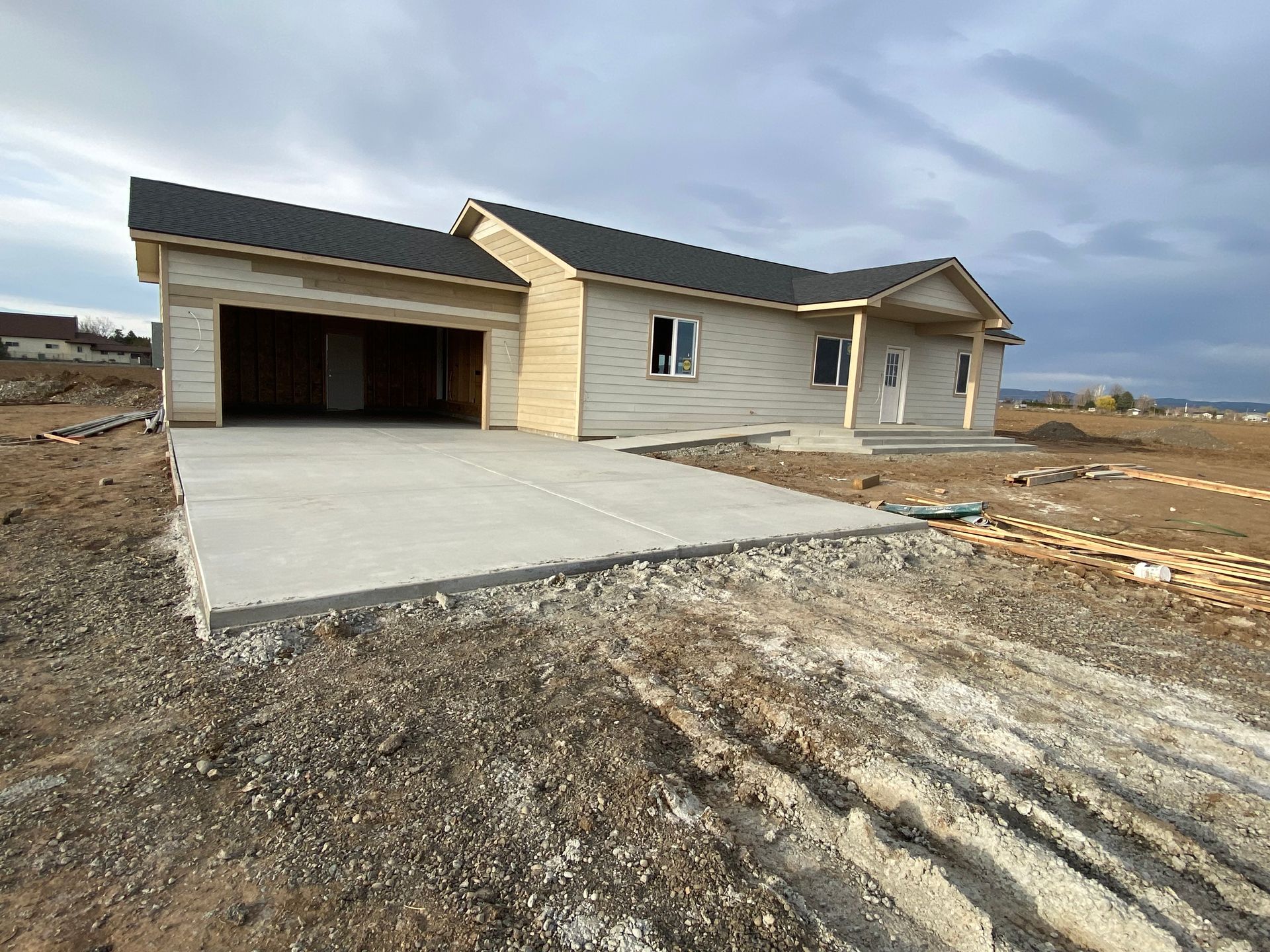 A house under construction with a concrete driveway in front of it.