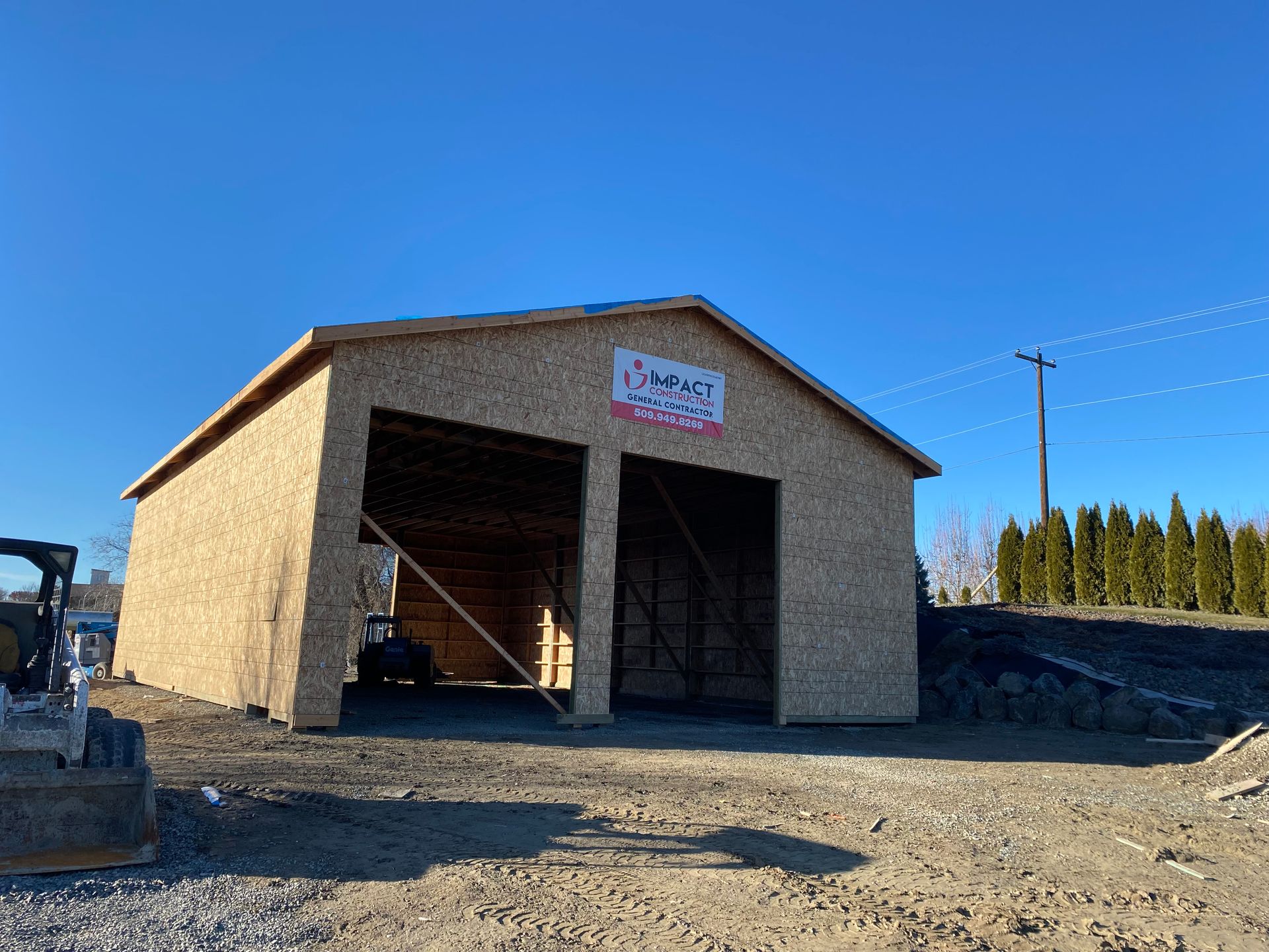 A large wooden garage is being built in a dirt field.