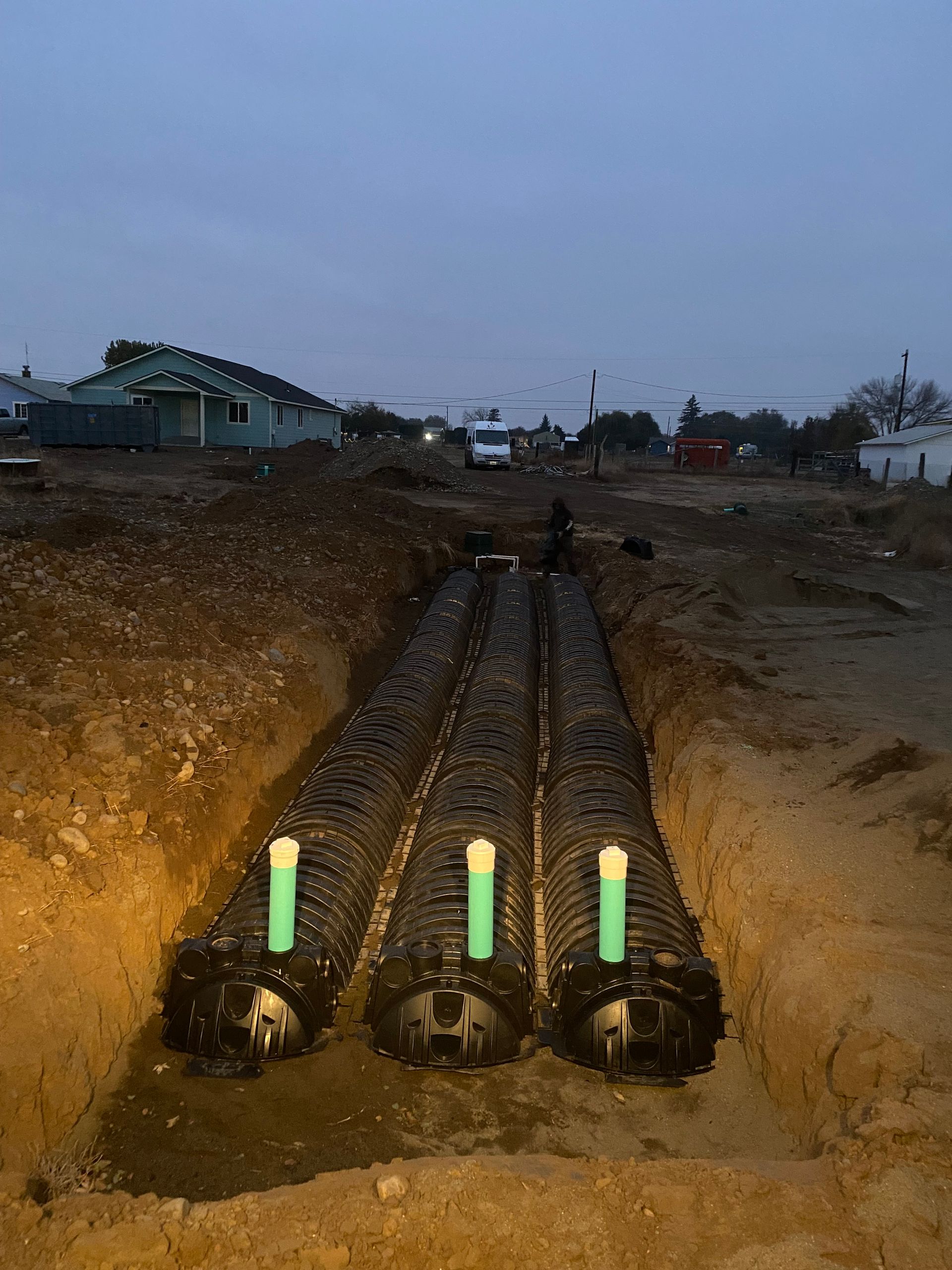 A row of pipes are sitting in the dirt in a trench.