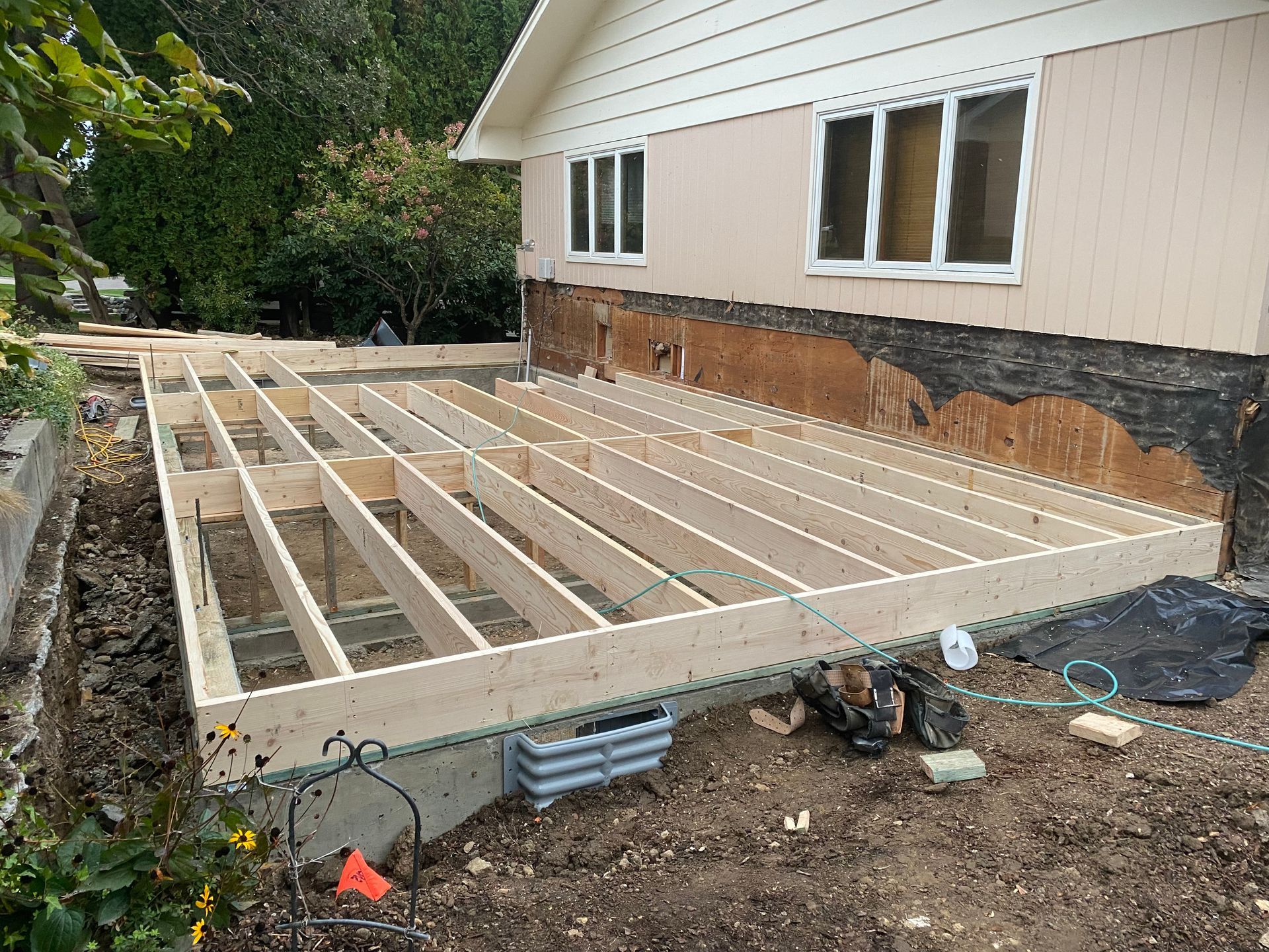 A wooden deck is being built on the side of a house.