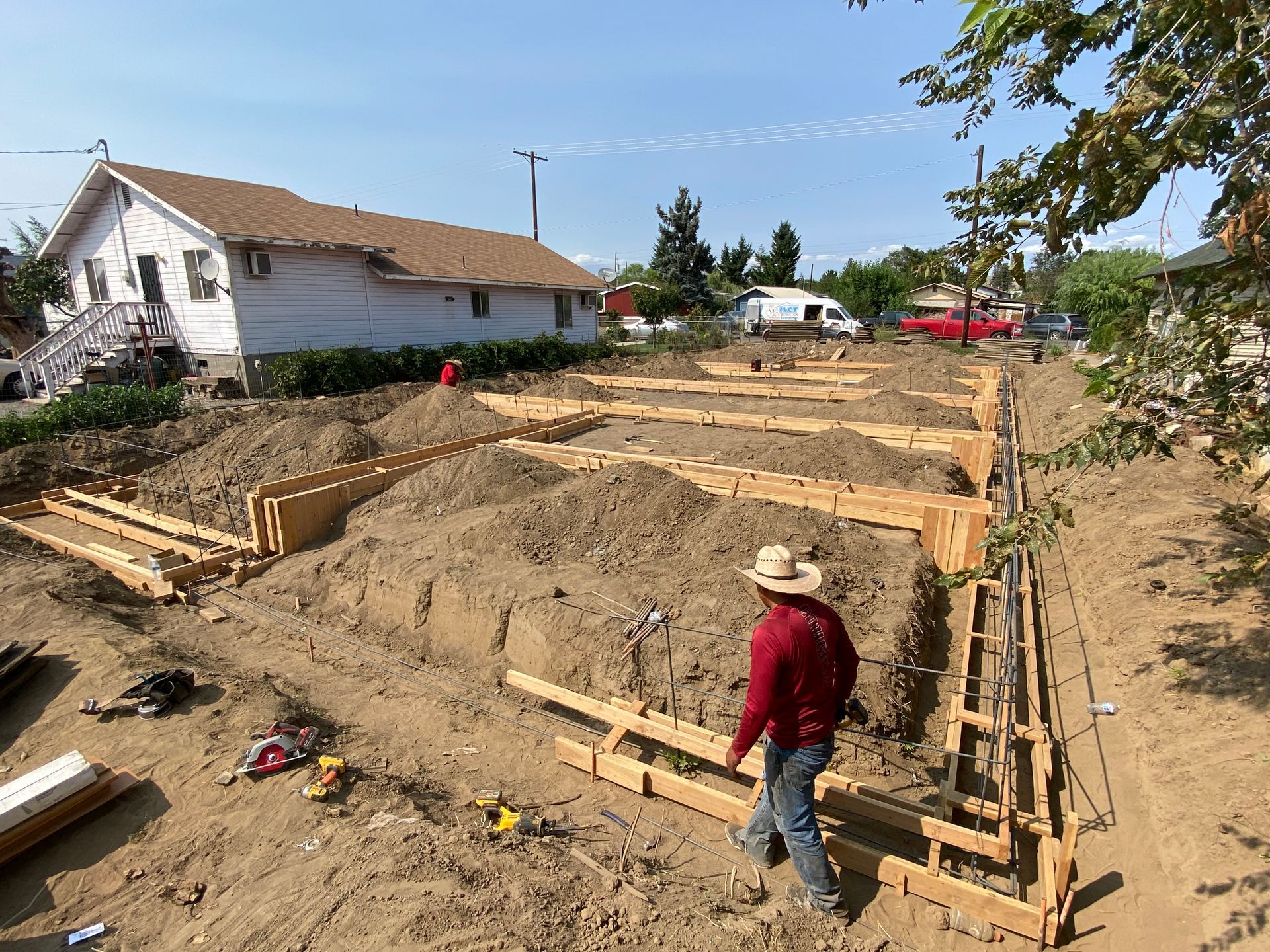 A man in a cowboy hat is standing in the dirt in front of a house.