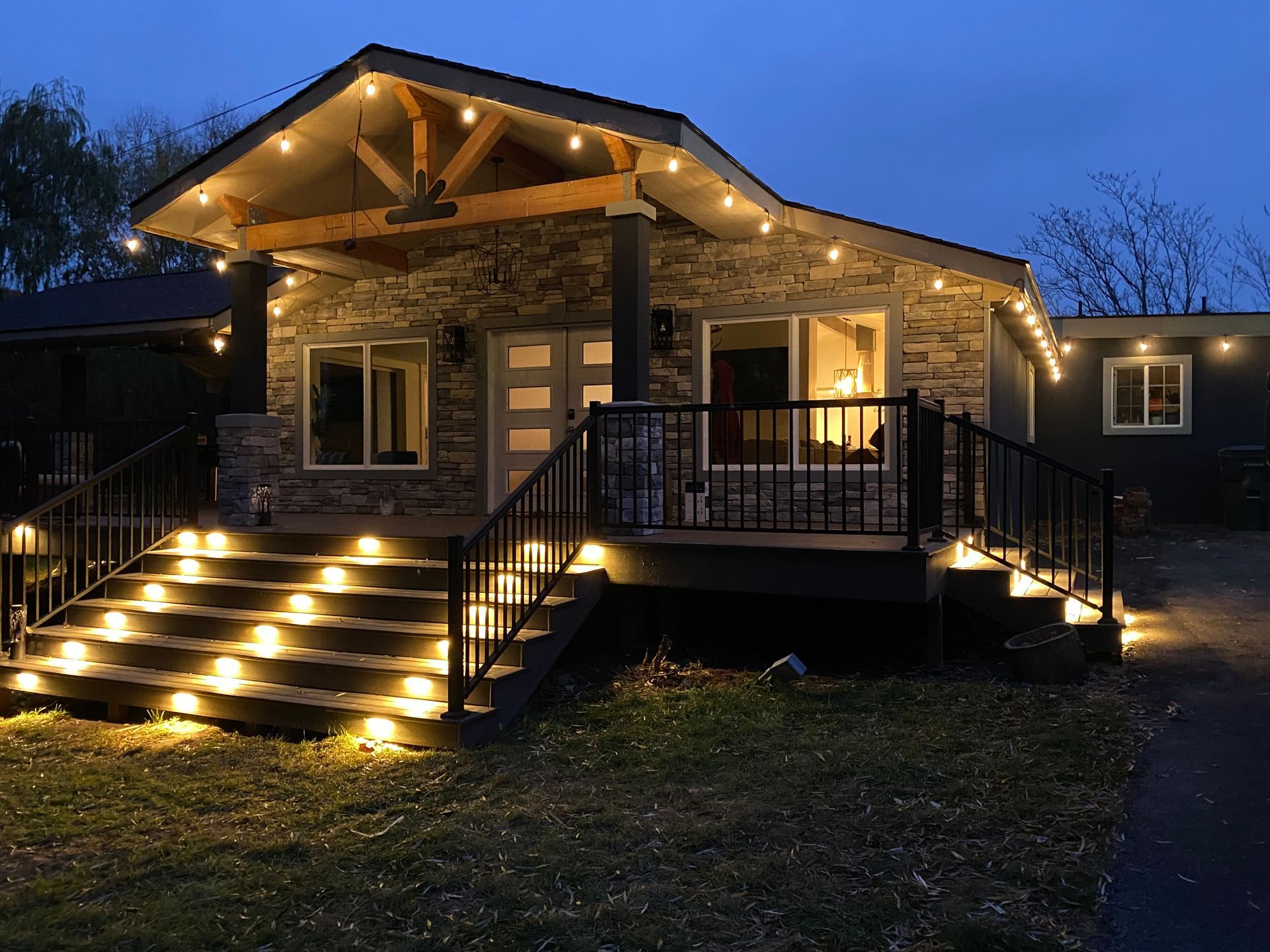 A house with stairs and a deck is lit up at night.