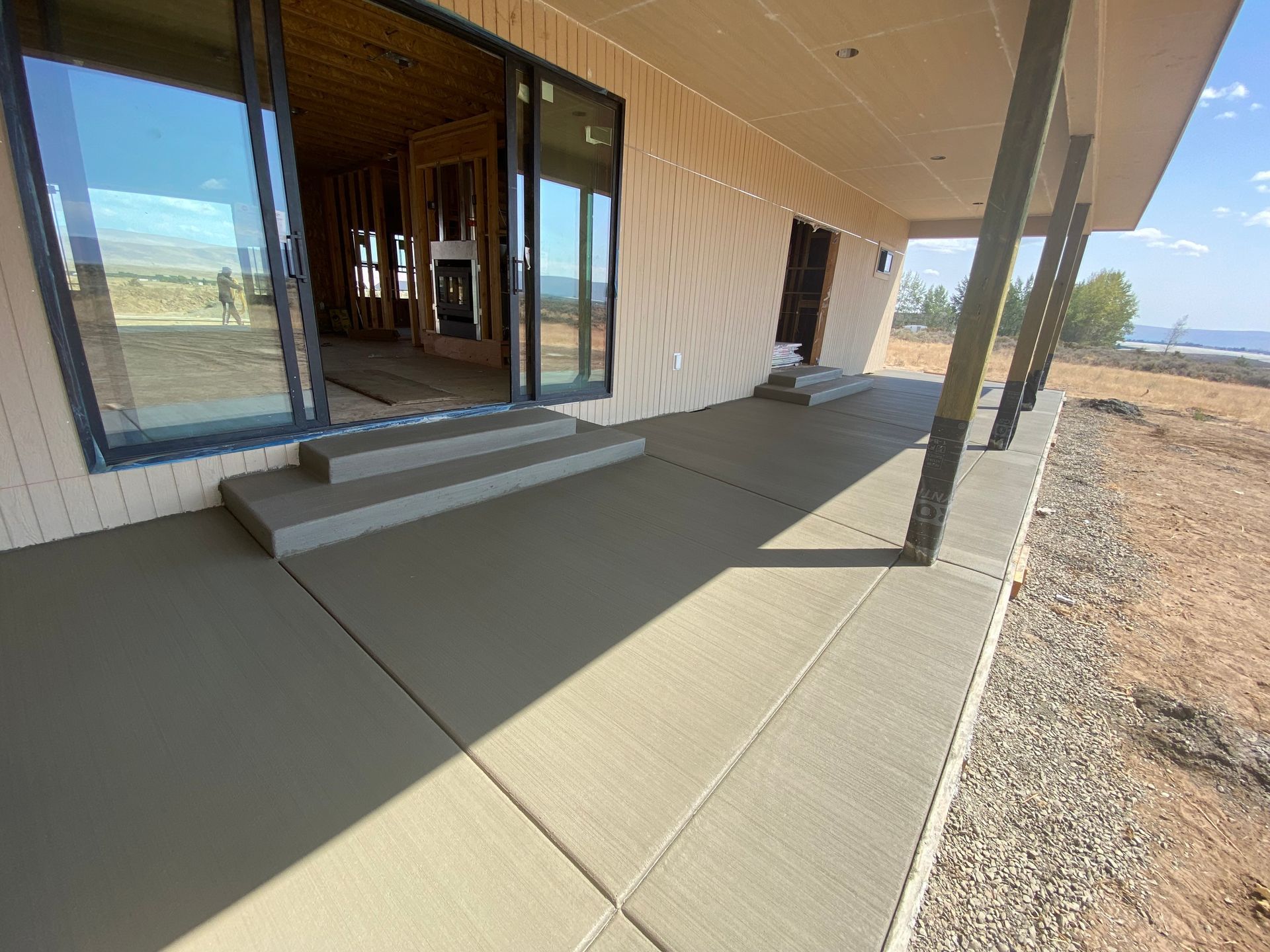 A concrete porch with steps leading to a house under construction.