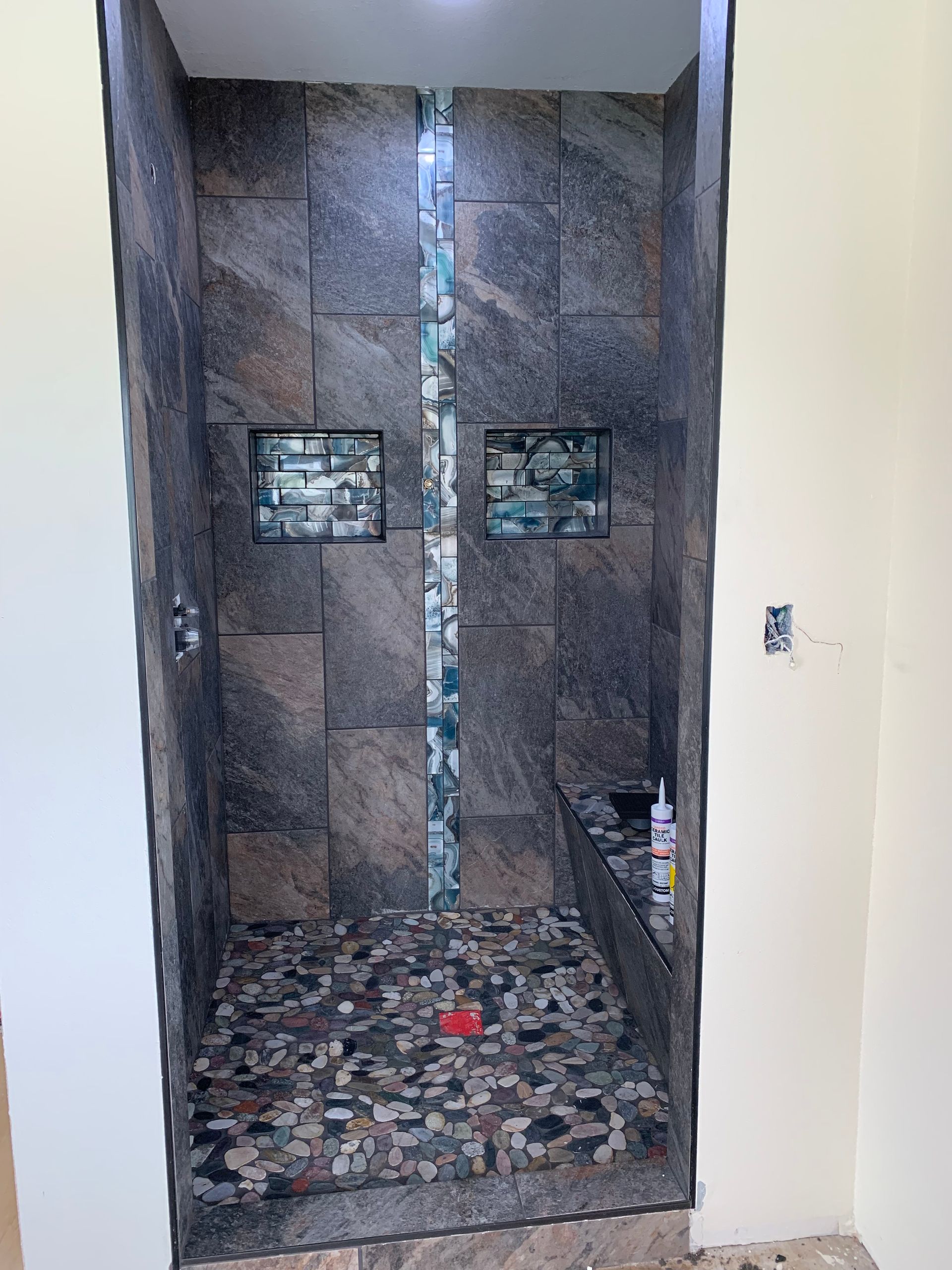 A bathroom with a walk in shower and a tiled floor.