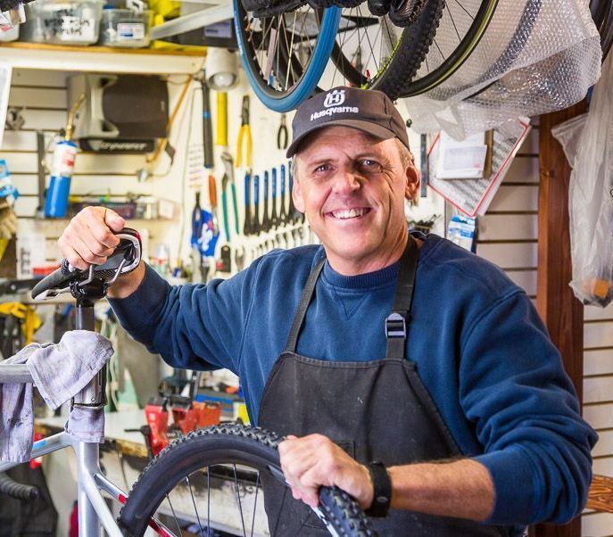 A man wearing an apron is working on a bicycle