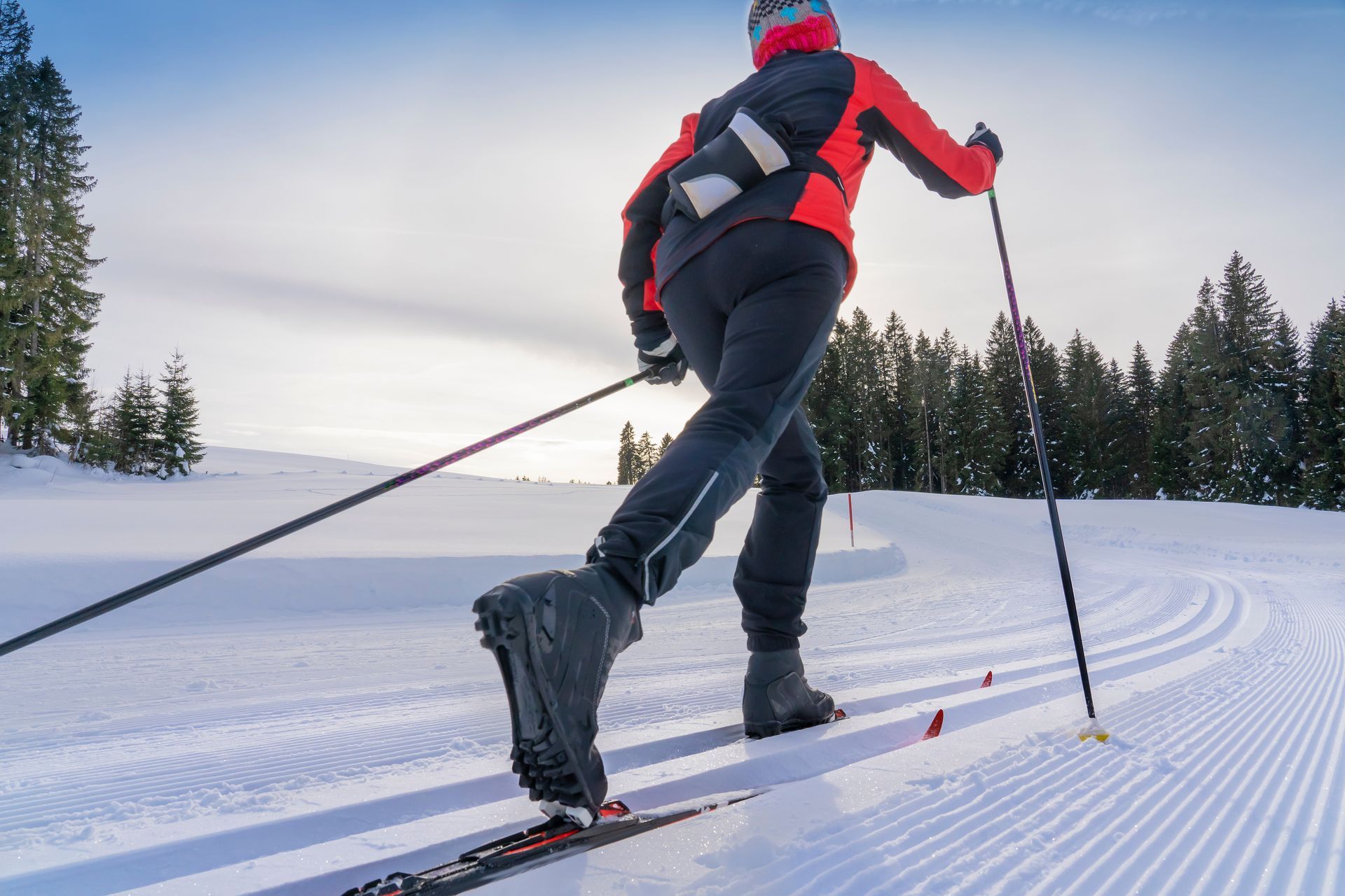 A person is cross country skiing down a snow covered slope.