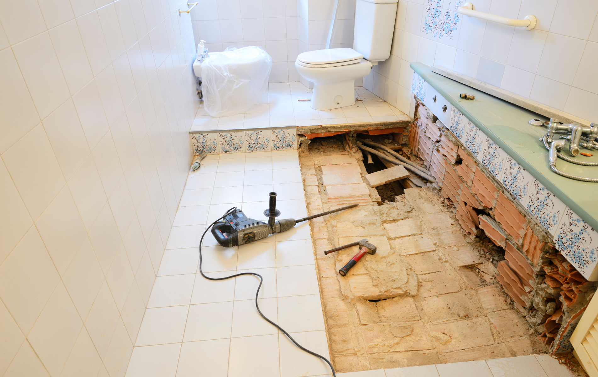 A bathroom is being remodeled with a drill on the floor.
