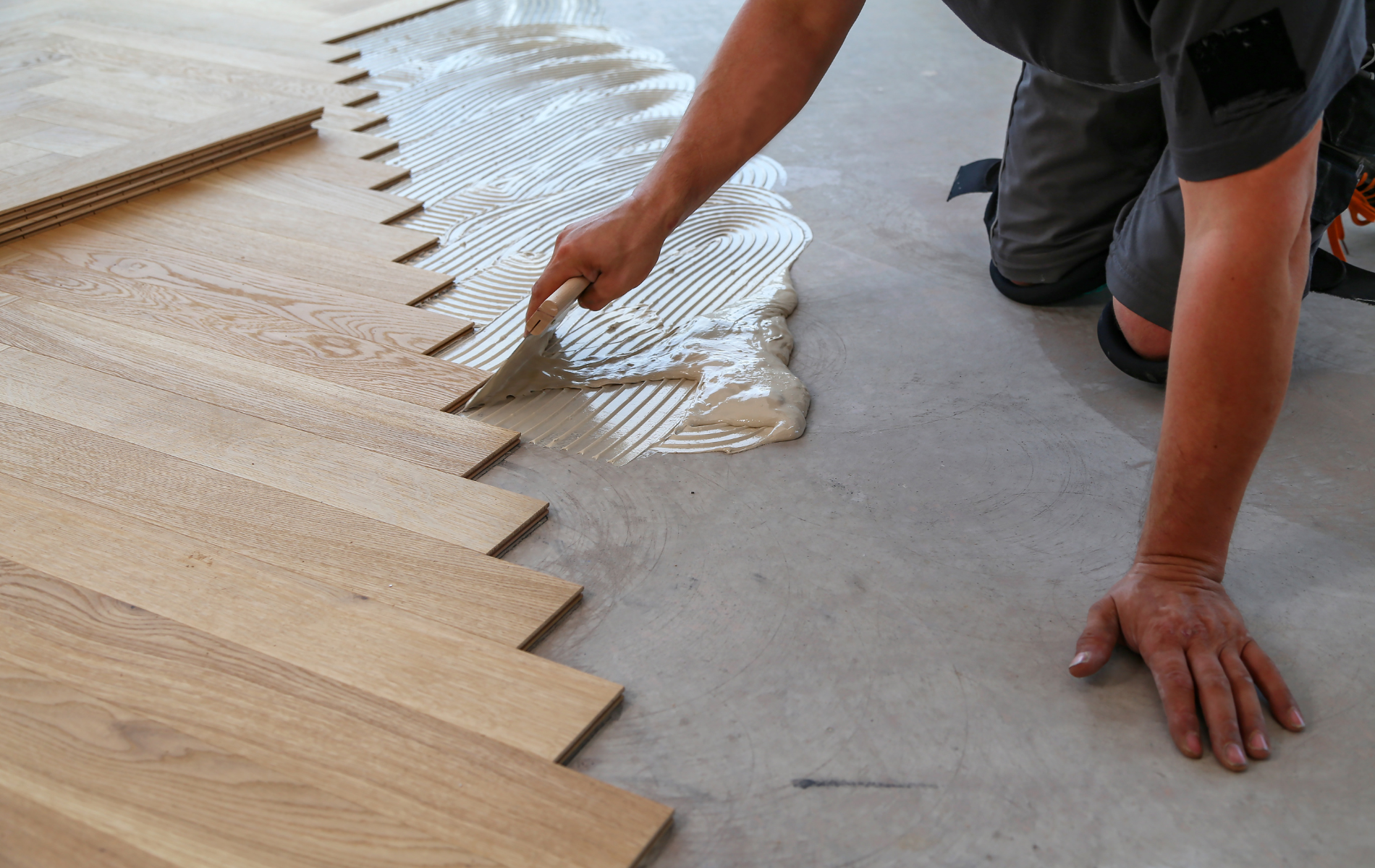A man is applying glue to a wooden floor.