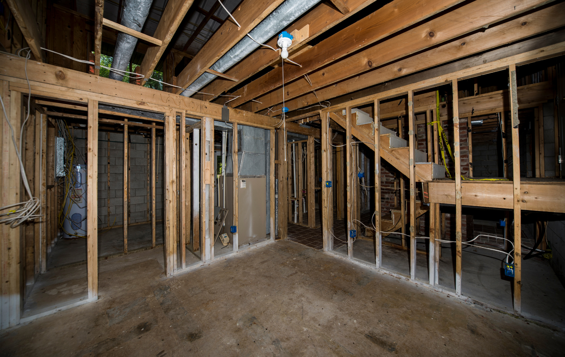 An empty basement with wooden beams and a staircase.