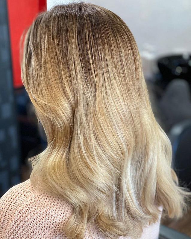 A Woman With Long Blonde Hair Is Wearing a Pink Sweater — Capello Hair Design in Port Macquarie, NSW