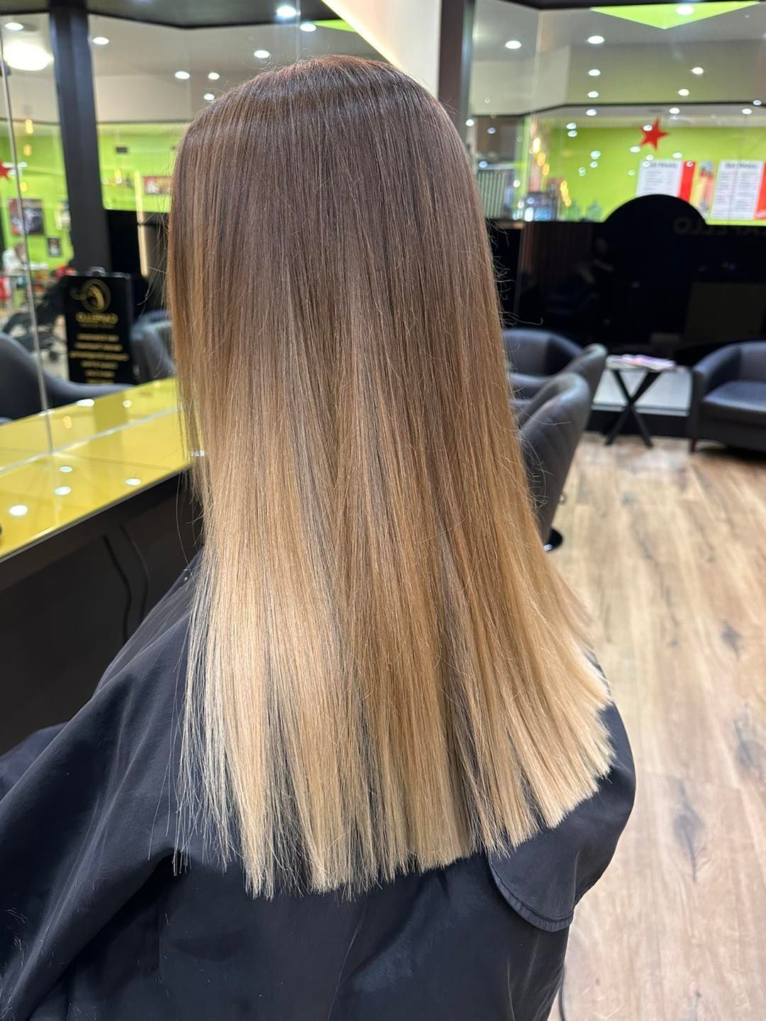 A Woman with Long Blonde Hair Is Sitting in A Chair — Capello Hair Design in Port Macquarie, NSW