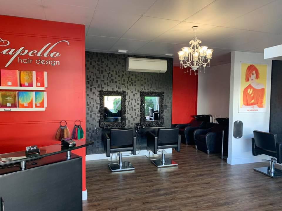 A Hair Salon With A Red Wall and Black Chairs — Capello Hair Design in Port Macquarie, NSW