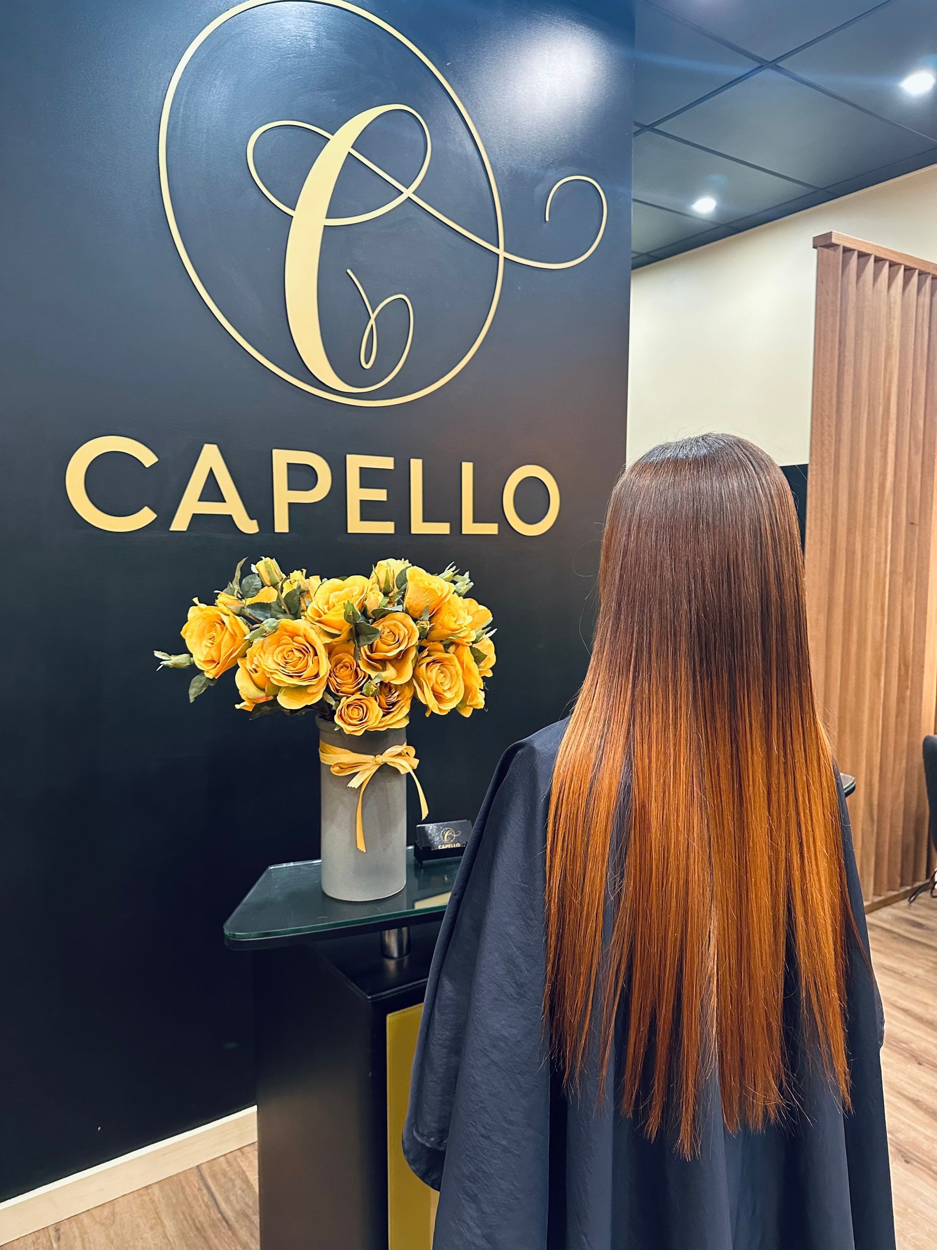 A Woman with Long Brown Hair Is Standing in A Salon — Capello Hair Design in Port Macquarie, NSW