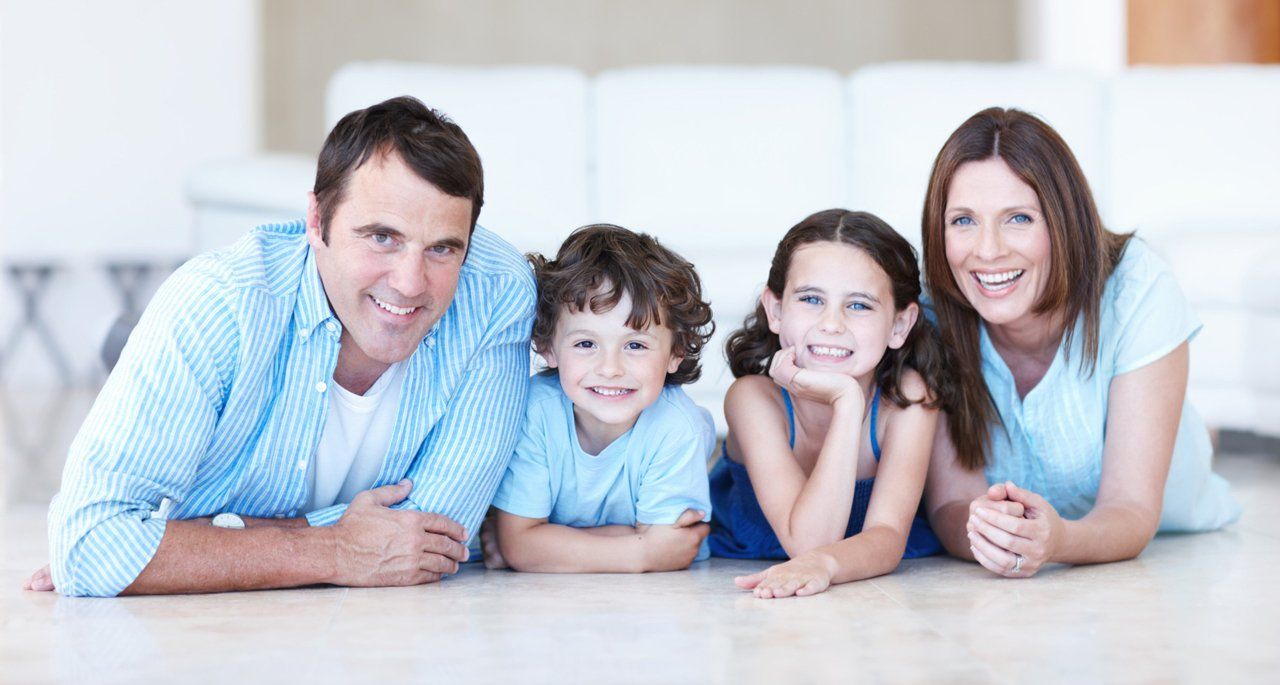 A family is laying on the floor in a living room.