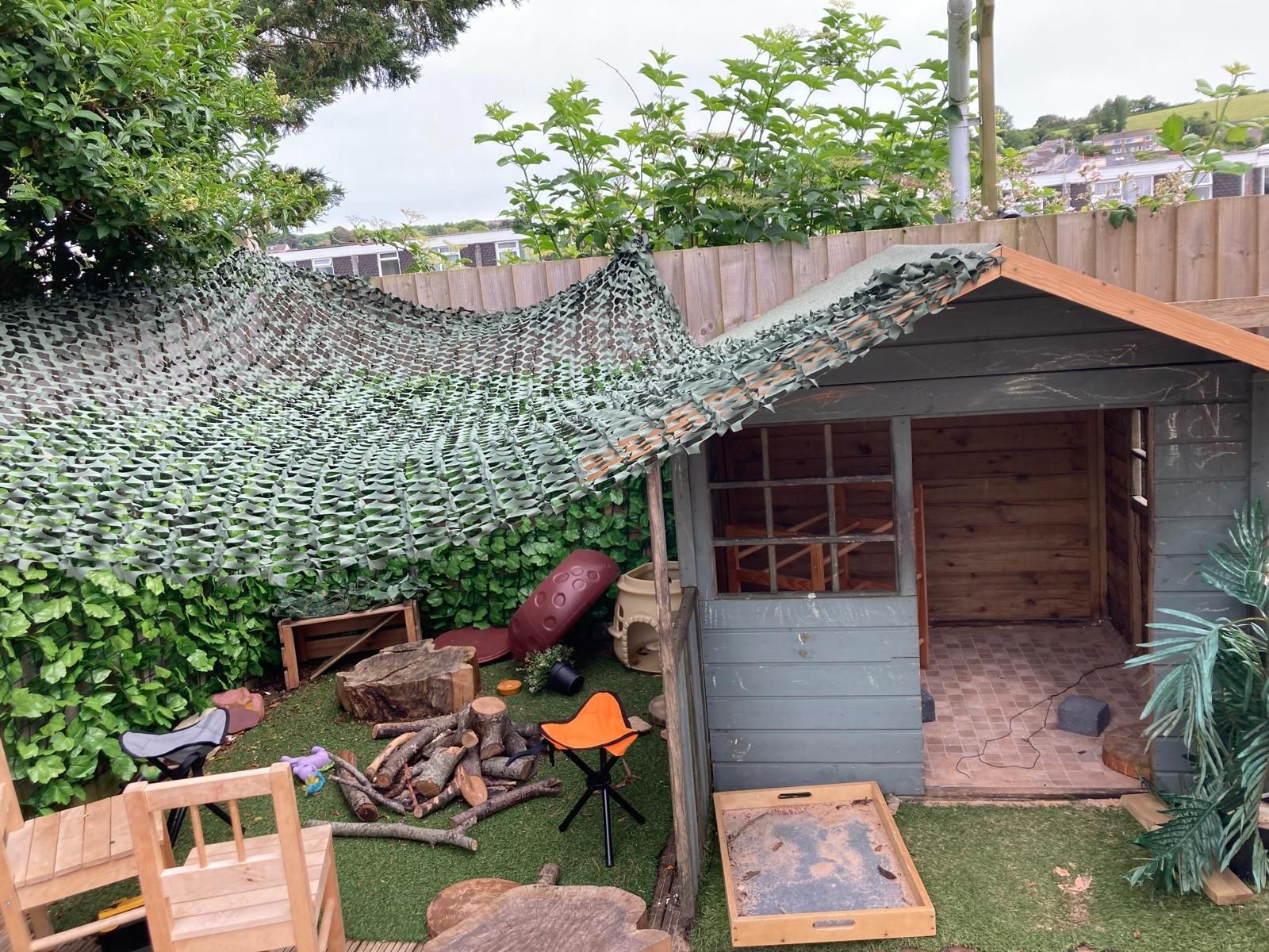 A wooden shed in a backyard with a camouflage roof