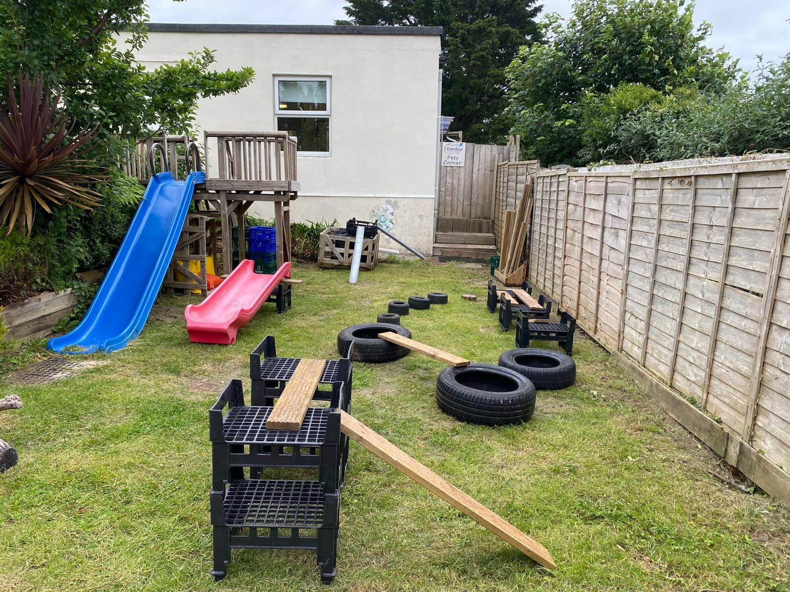 A backyard with a slide , chairs , and tires.