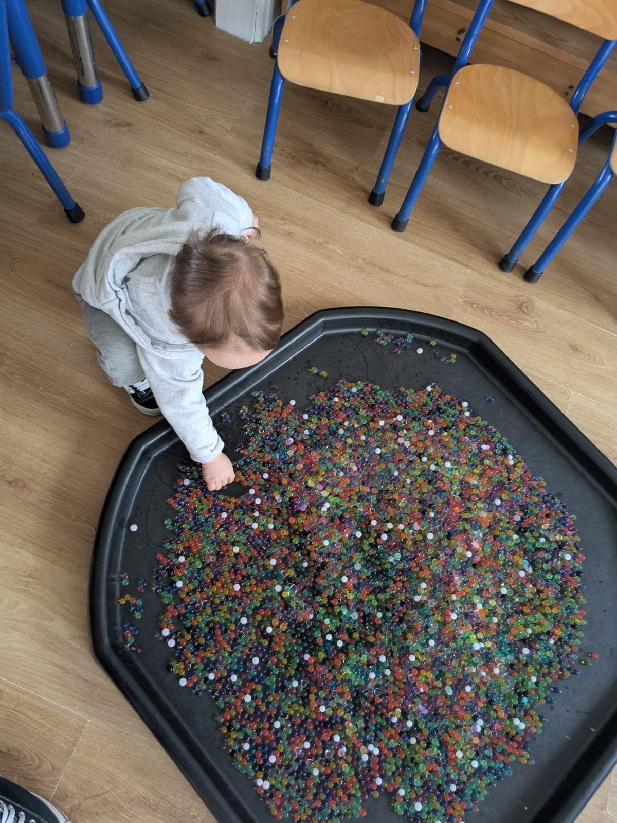 A child is playing with a pile of water beads