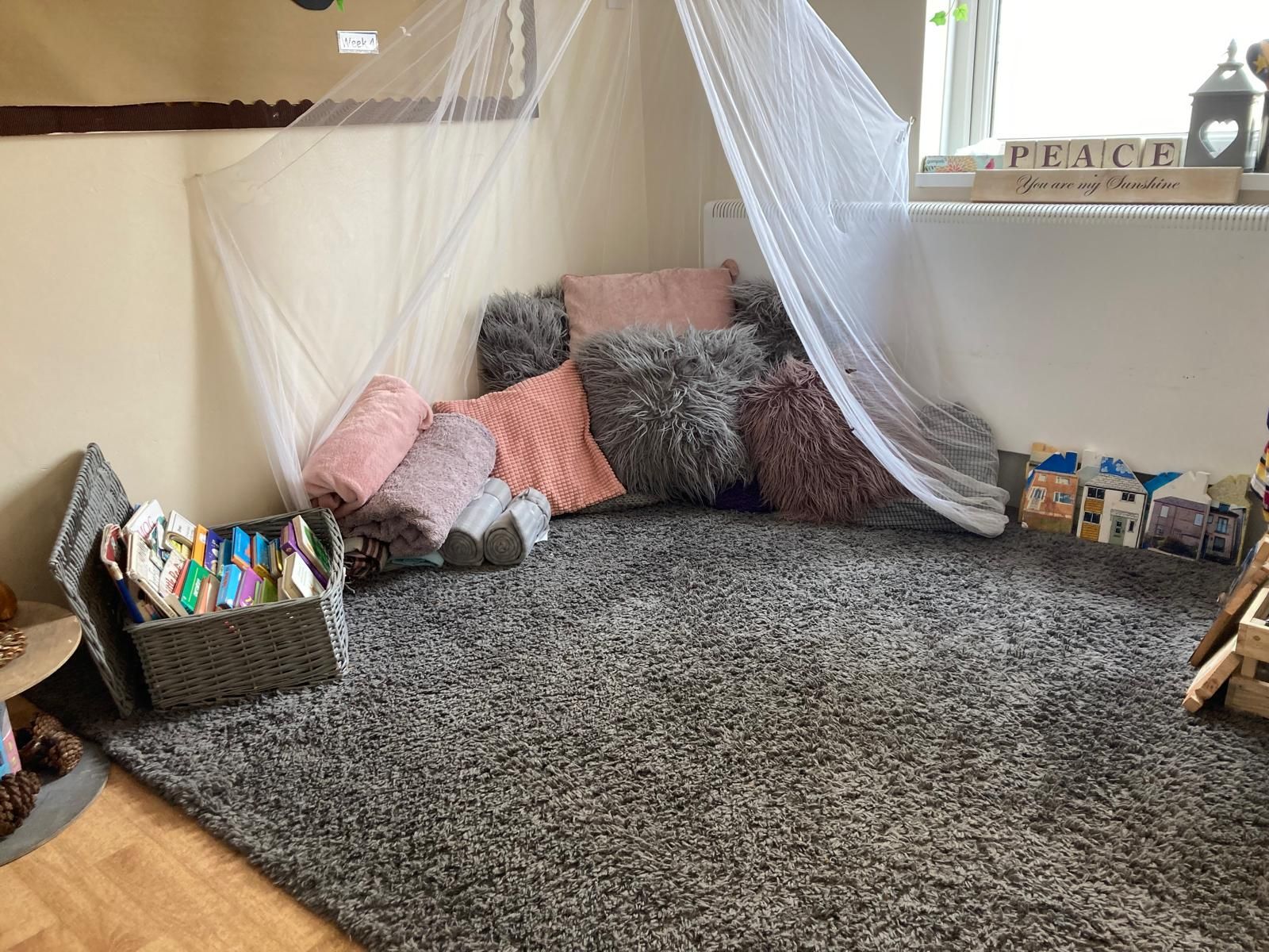 A room with a rug , pillows , a canopy and a window.