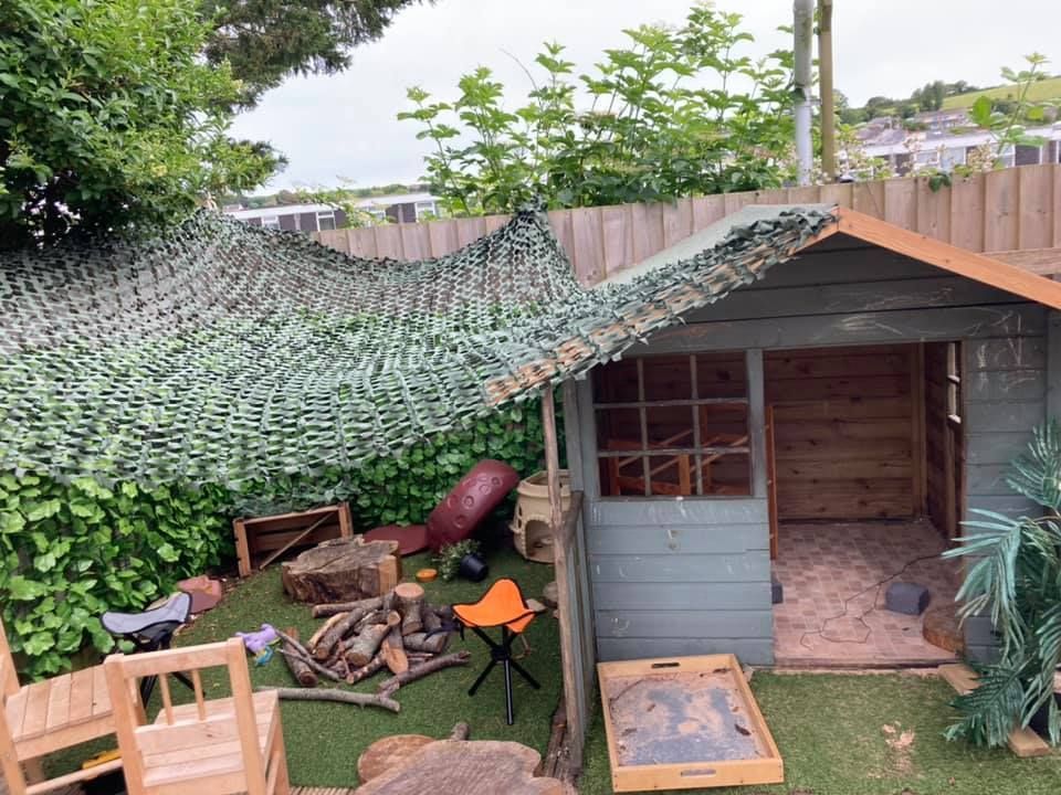 A wooden shed in a backyard with a camouflage roof