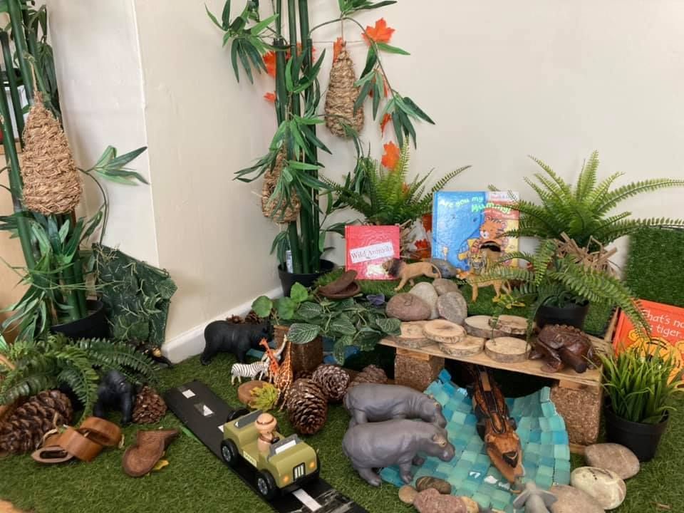 A toy car is driving down a road surrounded by plants and animals.