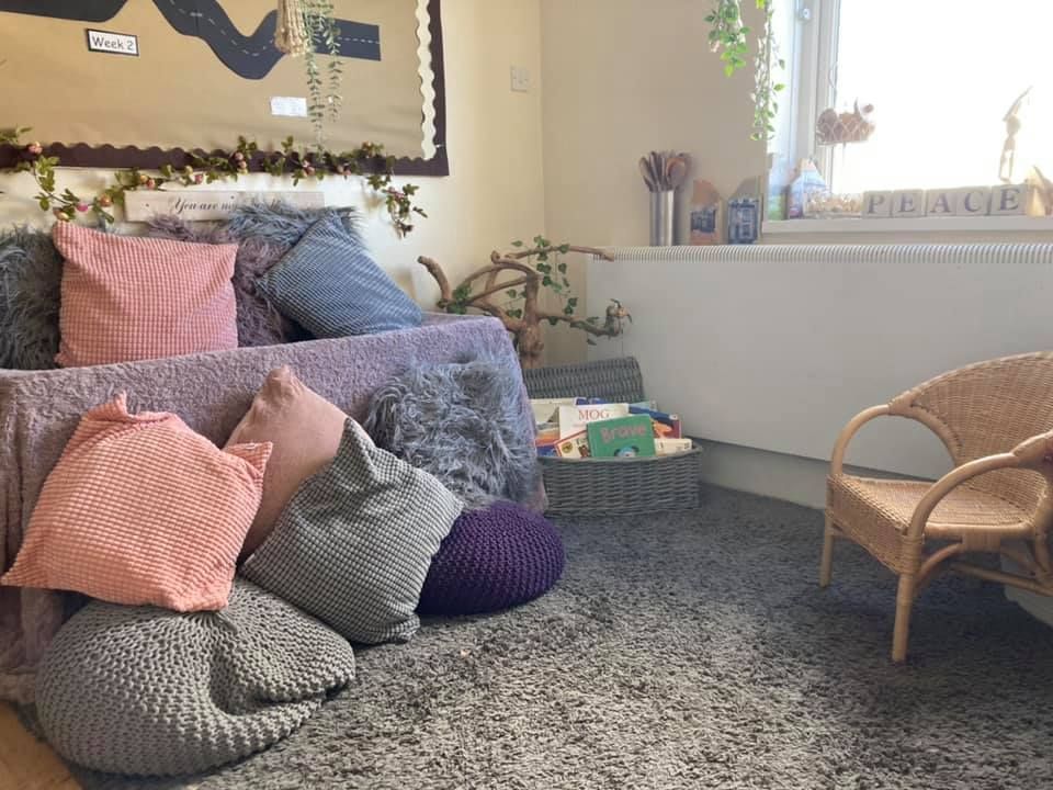 A room with a couch , chair , and pillows on the floor.