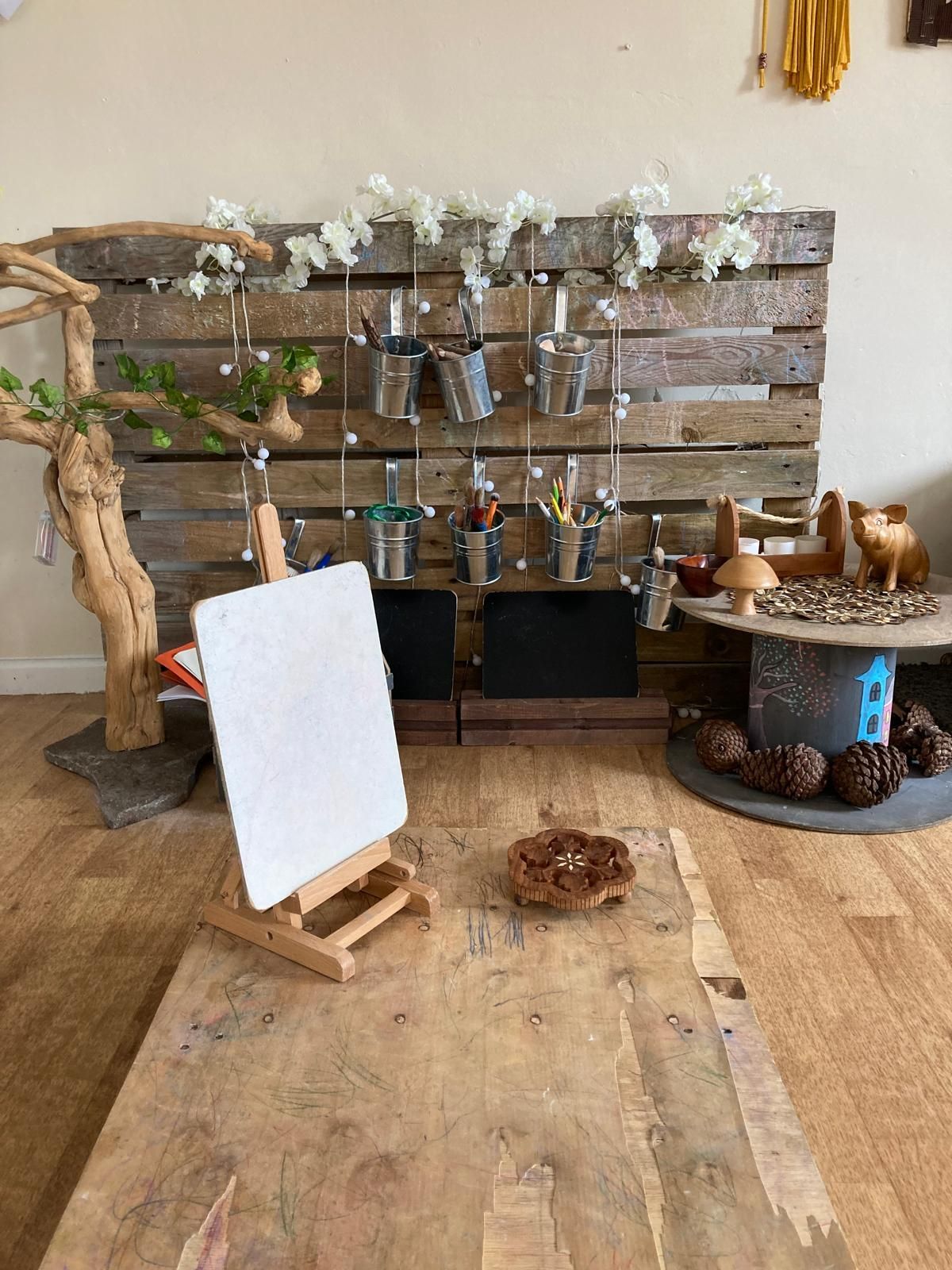A wooden table with a painting easel in front of a wooden wall.