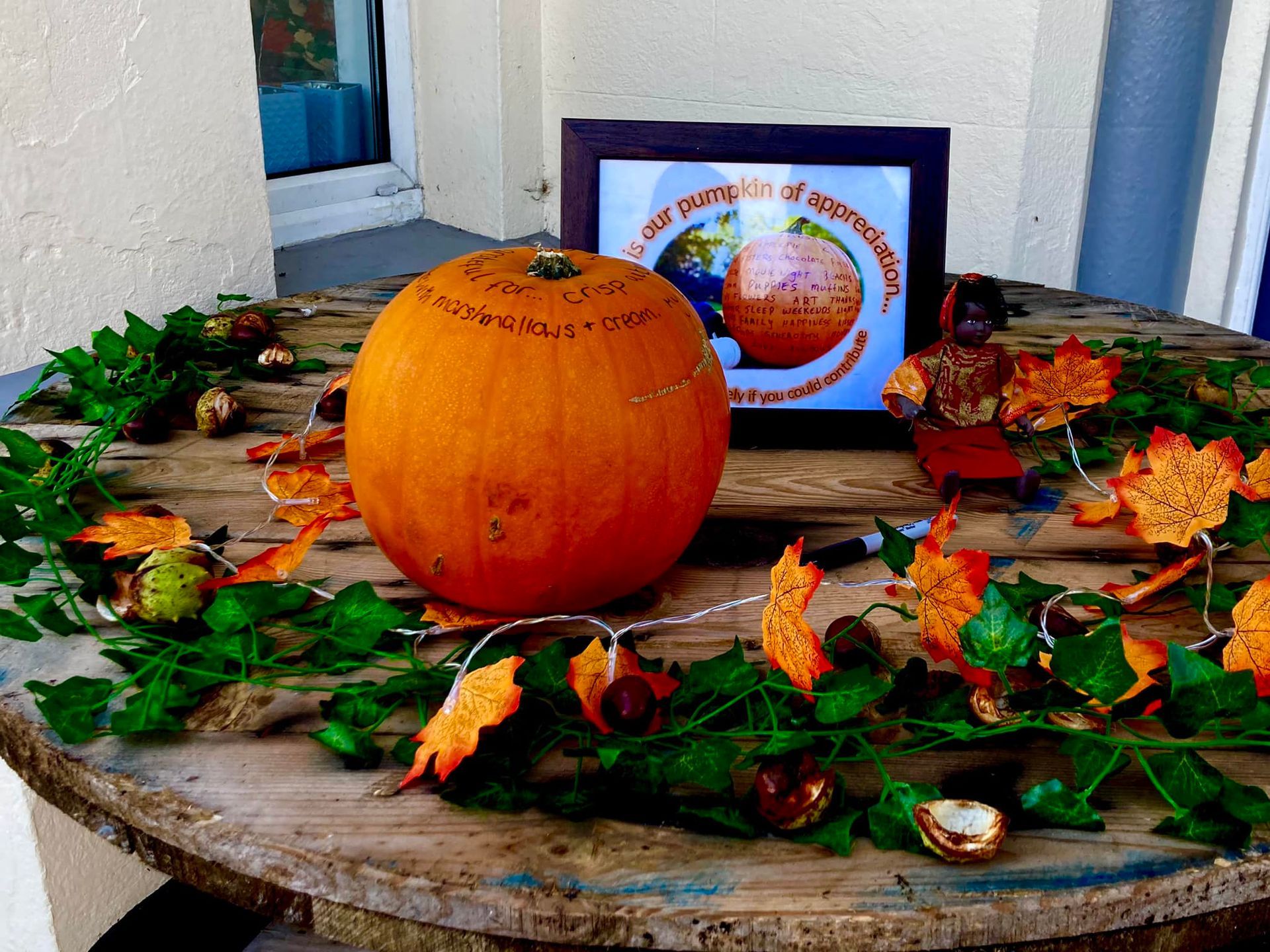 A pumpkin sits on a wooden table next to a picture of a pumpkin