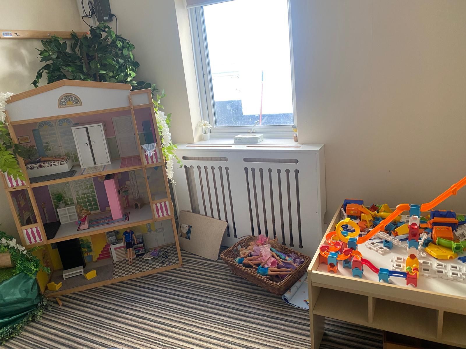 A room with a doll house and a table with toys on it