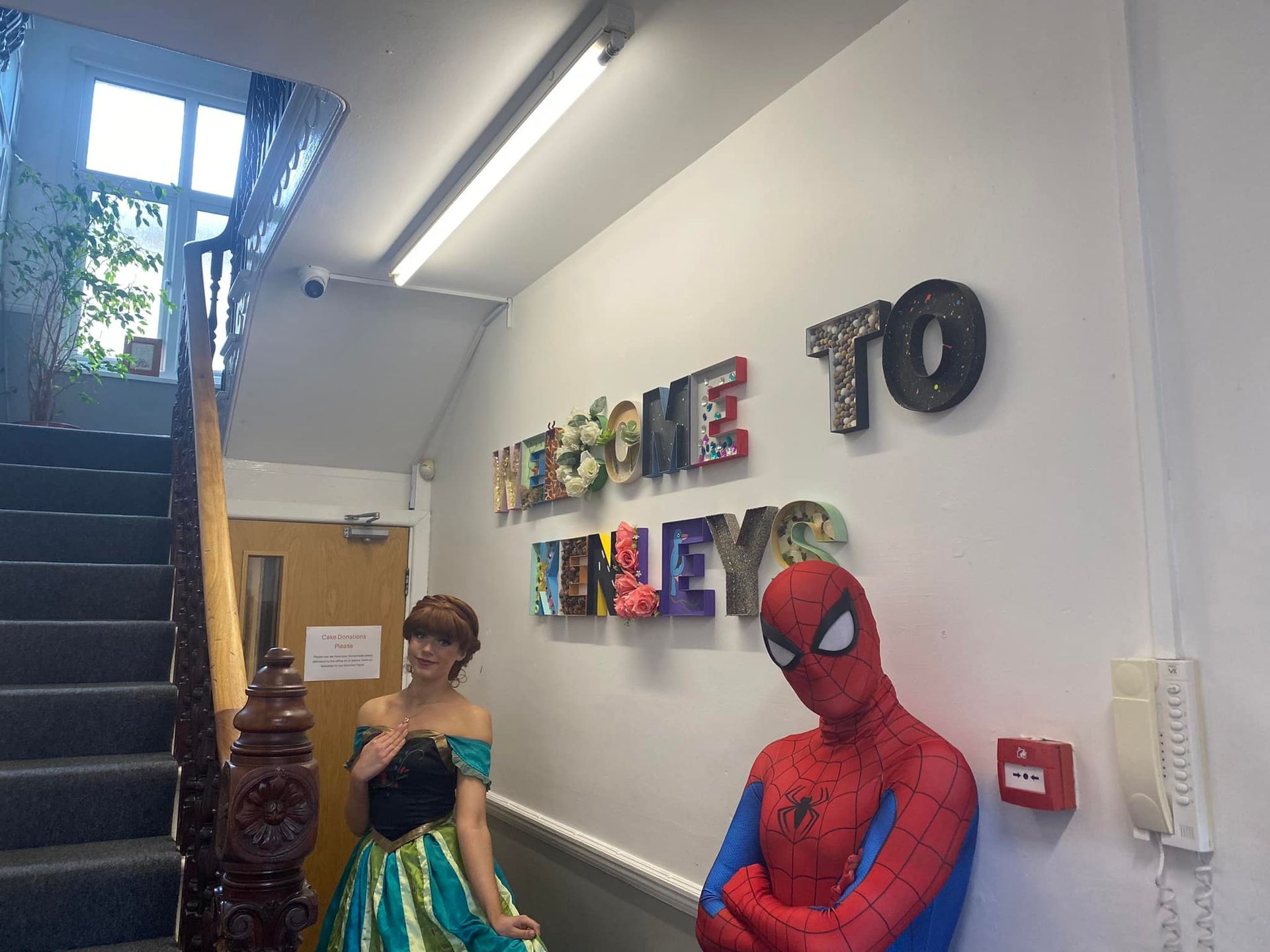 A spiderman and a princess are standing in front of a wall that says welcome to the eyes