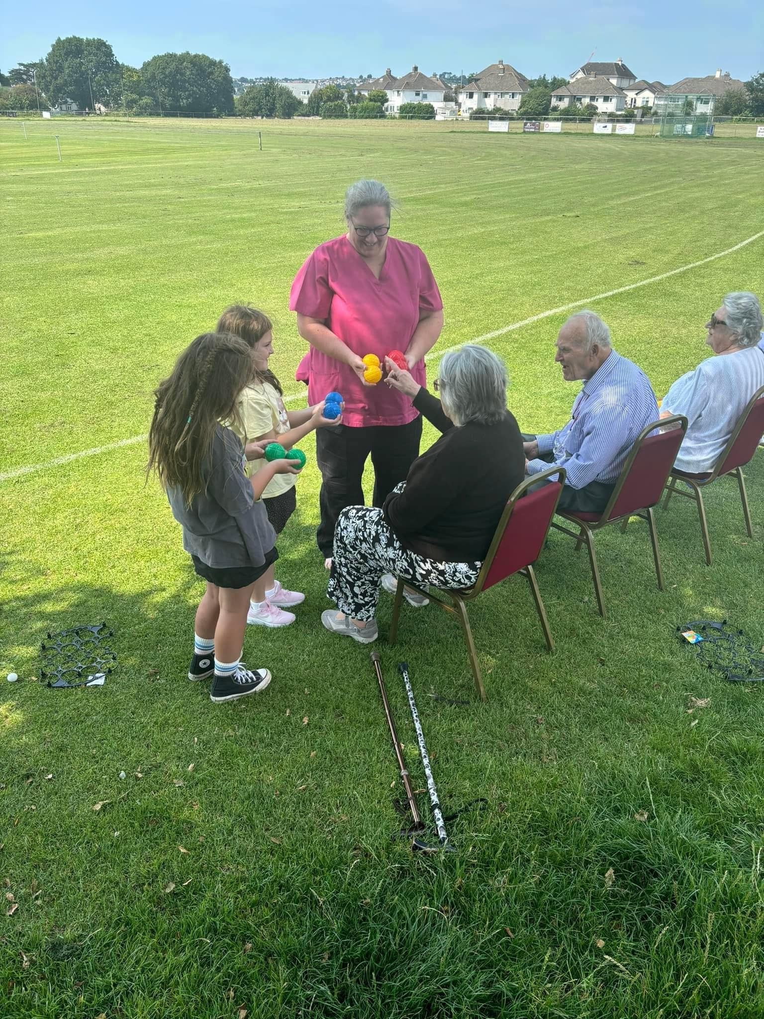 A group of people are sitting in chairs on a lush green field.