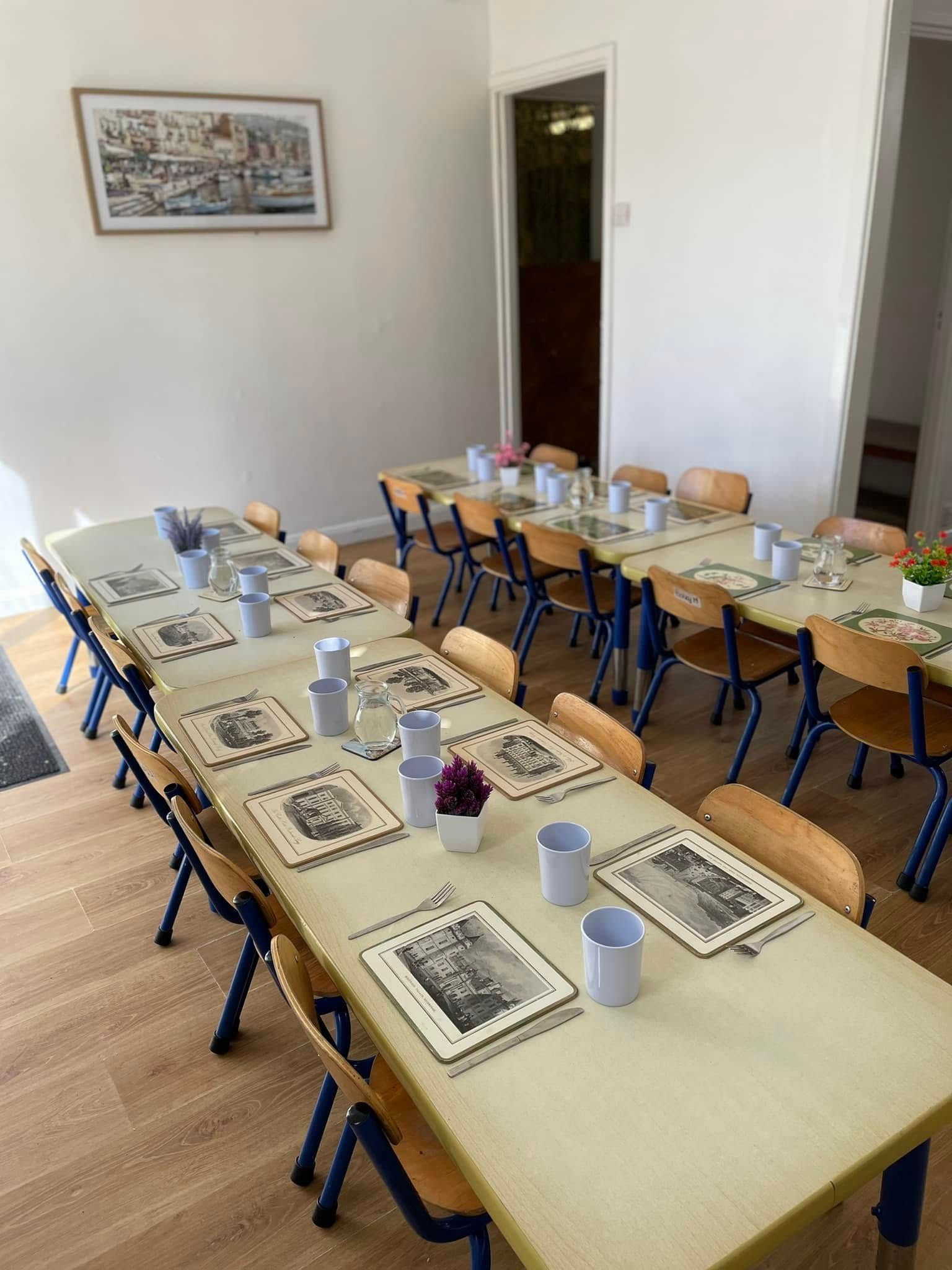 A room with tables and chairs and a picture on the wall