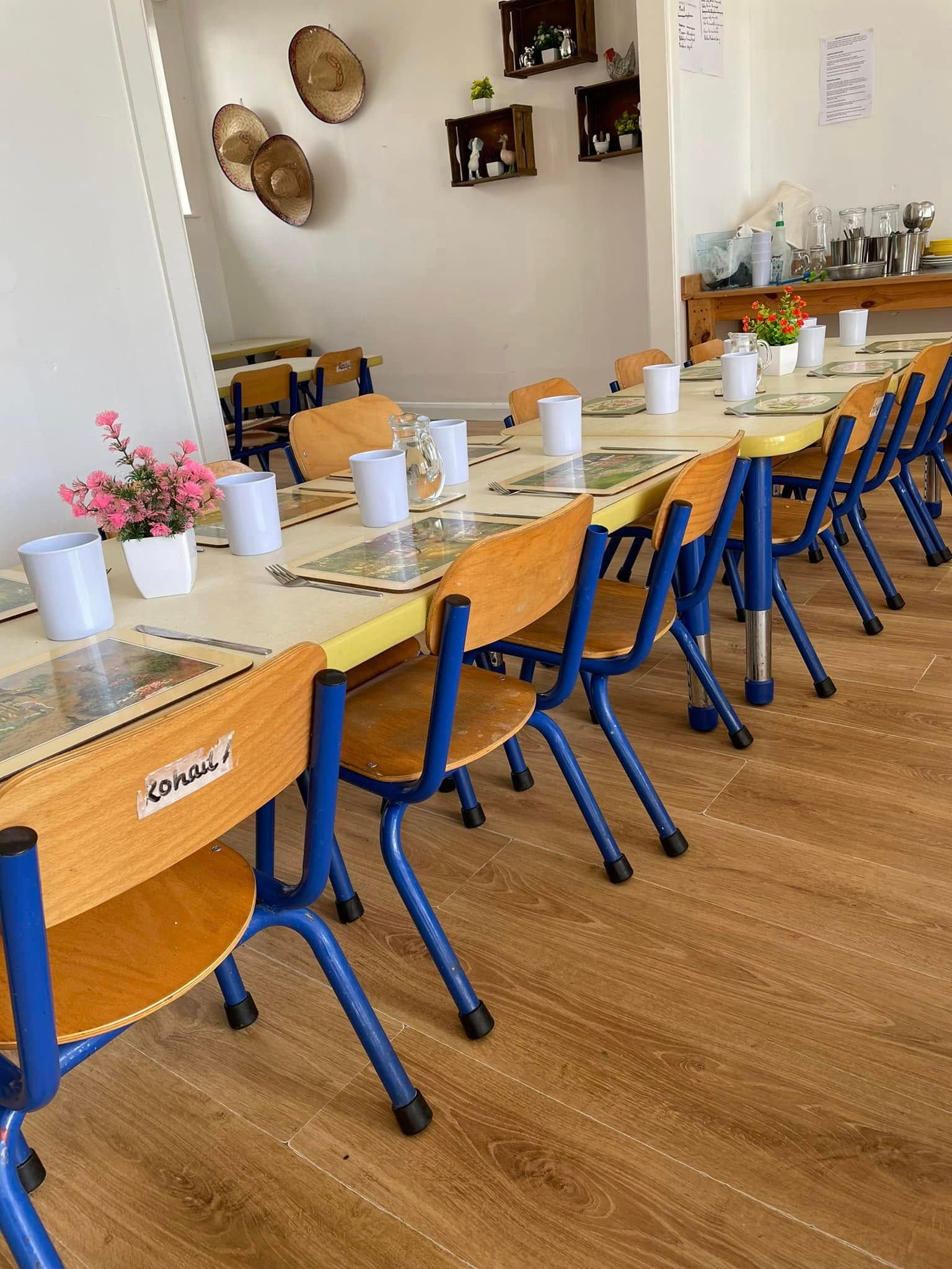 A long row of tables and chairs with flowers on them