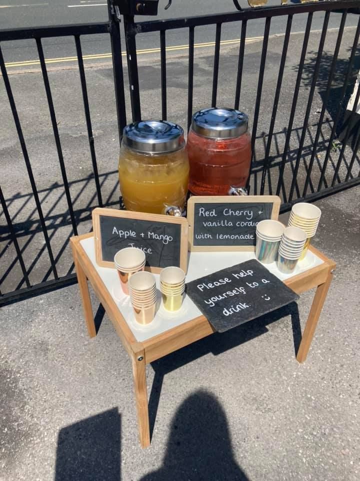 A small table with two drink dispensers and cups on it