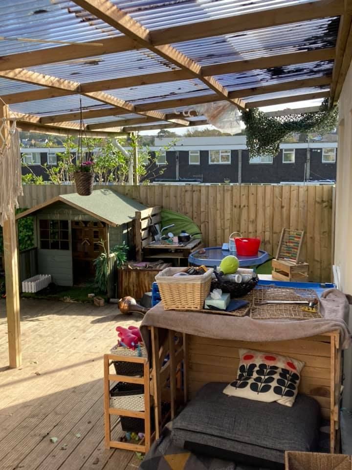 A wooden deck with a clear roof and a shed in the background