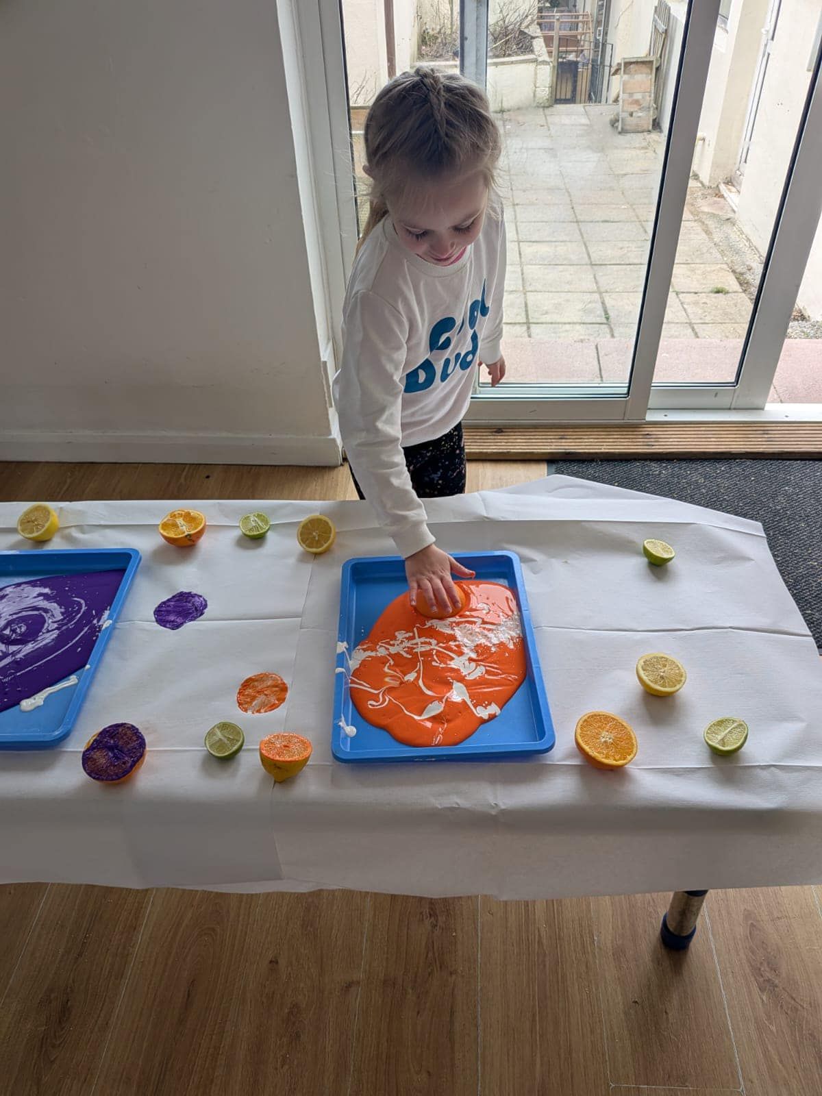 A little girl is playing with orange slime on a table