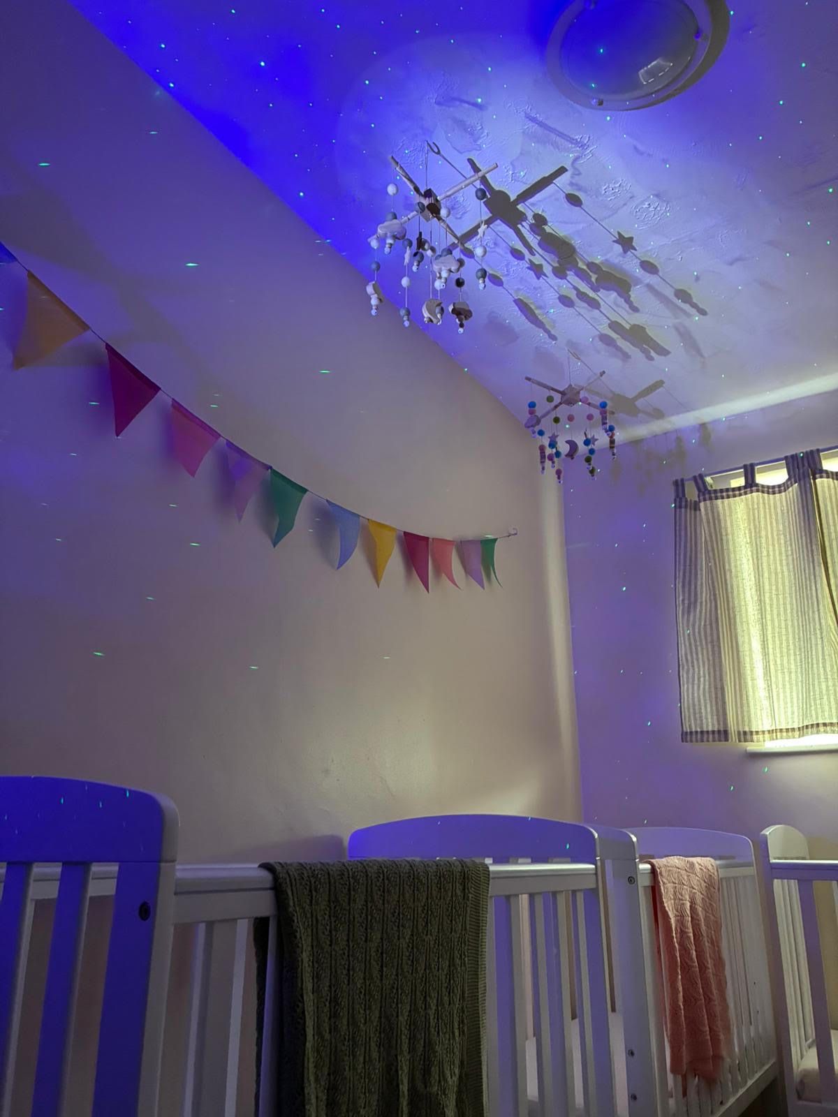 A baby 's room with a crib and a chandelier hanging from the ceiling.