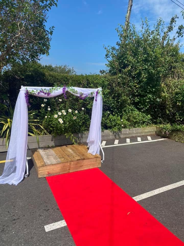 There is a red carpet leading to a wedding arch.