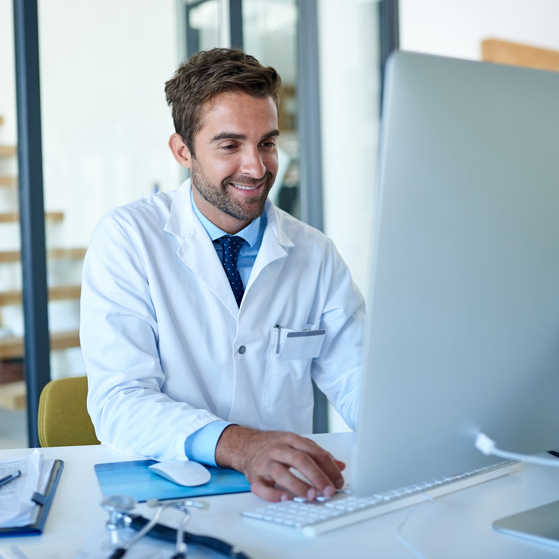 A doctor is sitting at a desk using a computer.