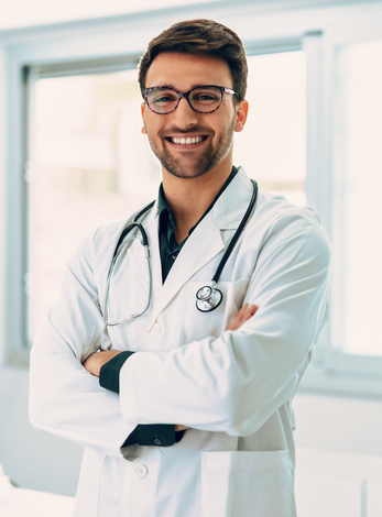 A doctor with a stethoscope around his neck is smiling with his arms crossed.