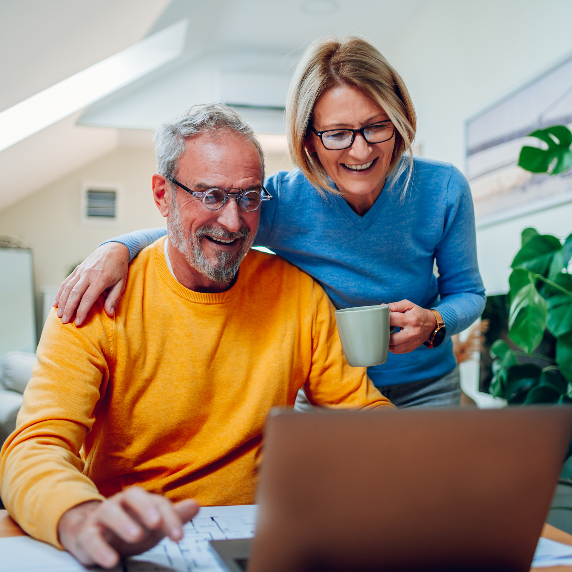 A man and a woman are looking at a laptop computer.