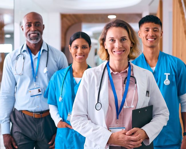 A group of doctors and nurses are standing next to each other in a hospital hallway.